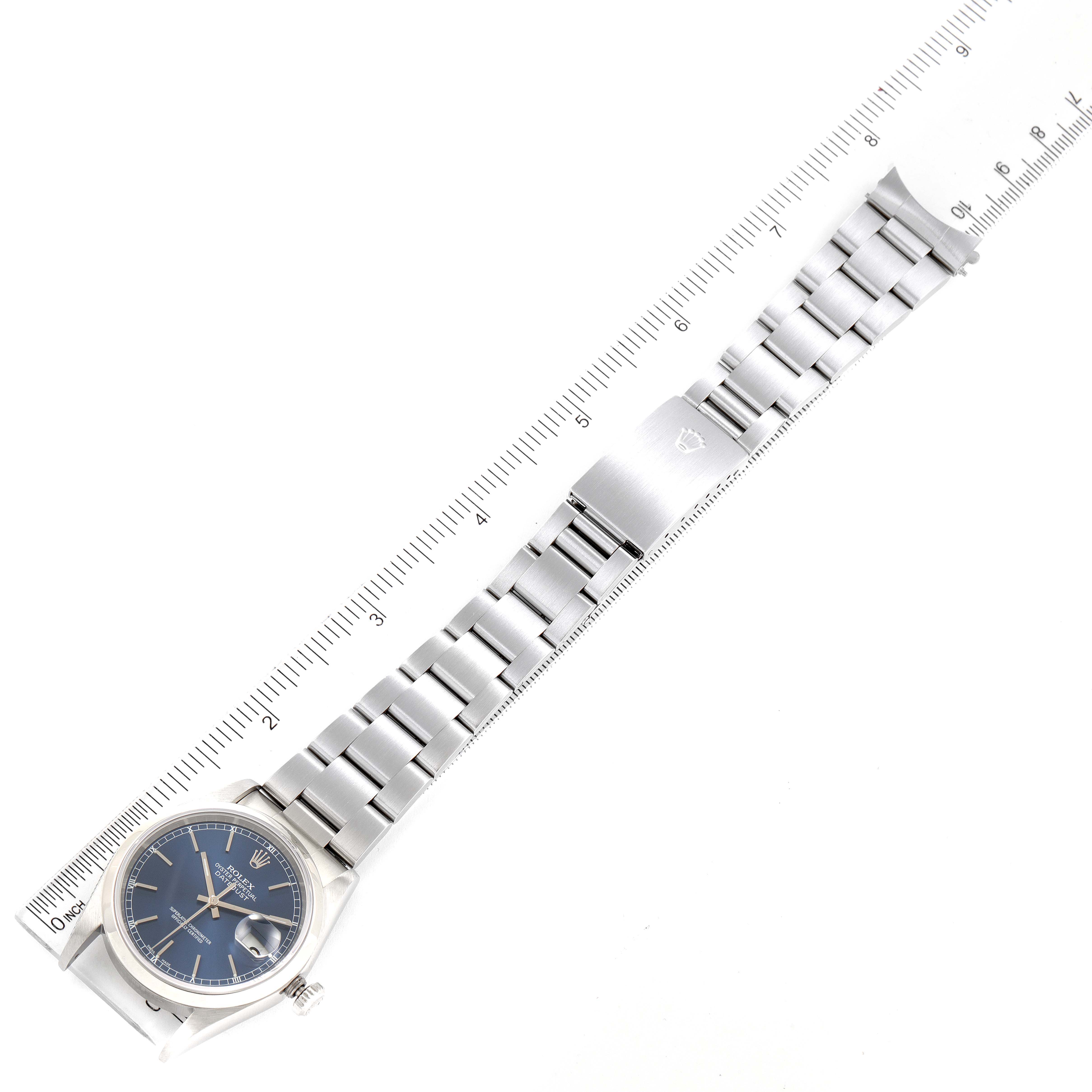 This image shows a Rolex Datejust 16200 Men's Stainless Steel Blue Dial 16200 Men's Stainless Steel Blue Dial watch laid flat alongside a ruler, highlighting its bracelet and clasp.