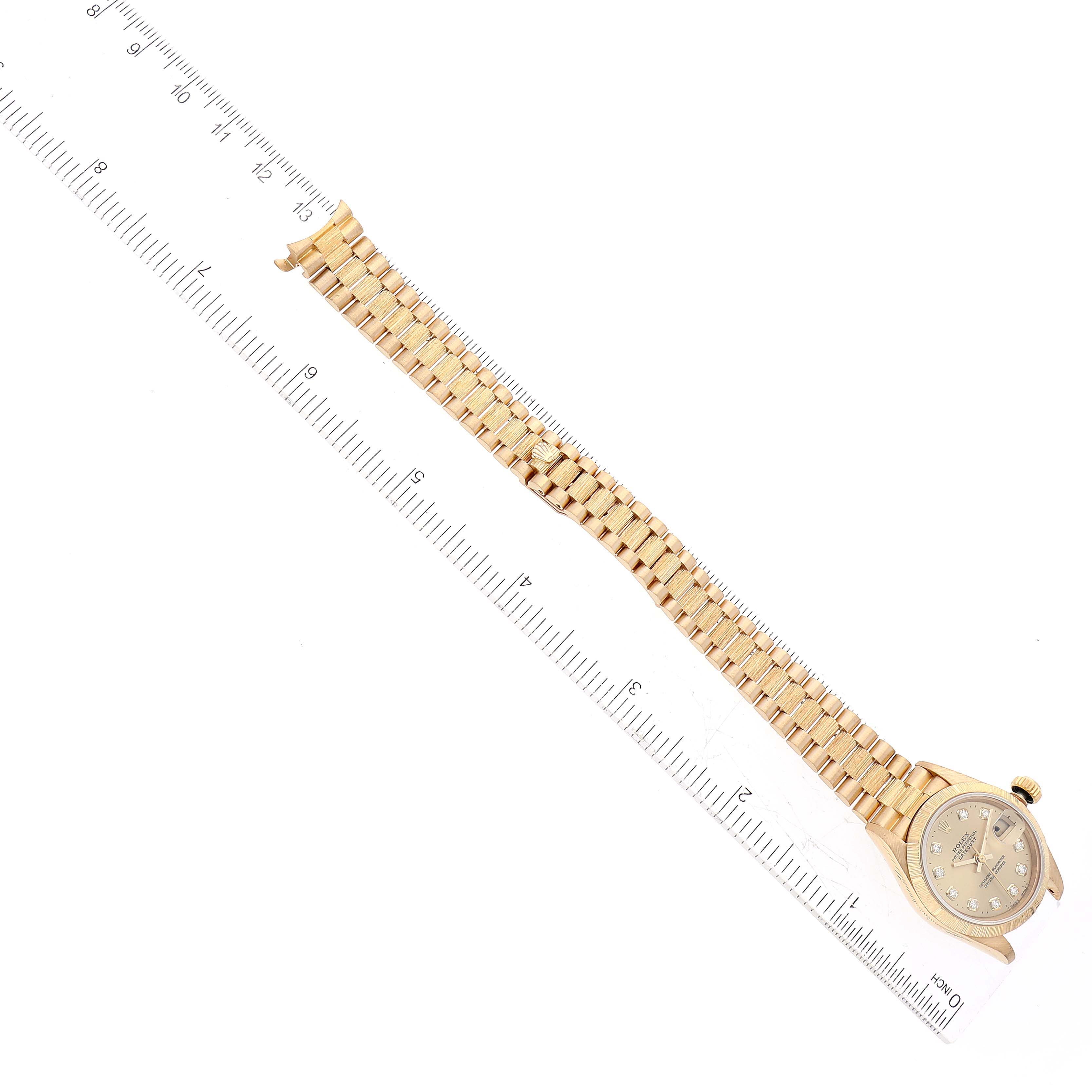 This image shows a Rolex President 69278 Women's Yellow Gold Champagne Dial 69278 Women's Yellow Gold Champagne Dial model watch at an overhead angle, highlighting its face and bracelet placed alongside a ruler.