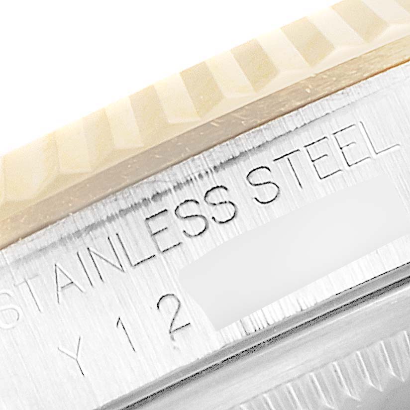 The image shows a close-up of the Rolex Datejust 16233 Men
s Steel and Gold (two tone) Grey Dial 16233 Men
s Steel and Gold (two tone) Grey Dial watch
s fluted bezel and part of the stainless steel case with engraving.