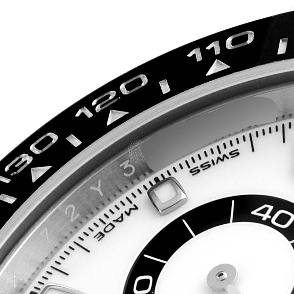 The image shows a close-up of the bezel and part of the dial of a Rolex Daytona 116500 Men's Stainless Steel White Dial 116500 Men's Stainless Steel White Dial watch.