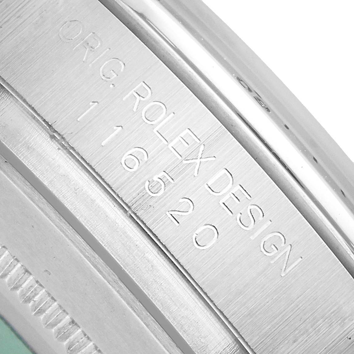 The image shows a close-up of the engraved model number "116520" and "ORG. ROLEX DESIGN" on a Rolex Daytona 116520 Men's Stainless Steel Black Dial watch.