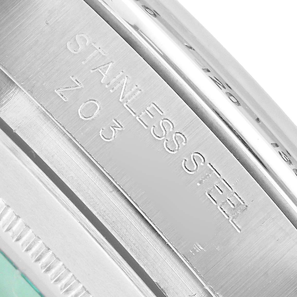 The image shows a close-up of the case edge of a Rolex Daytona 116520 Men's Stainless Steel Black Dial watch with "STAINLESS STEEL" engraved.