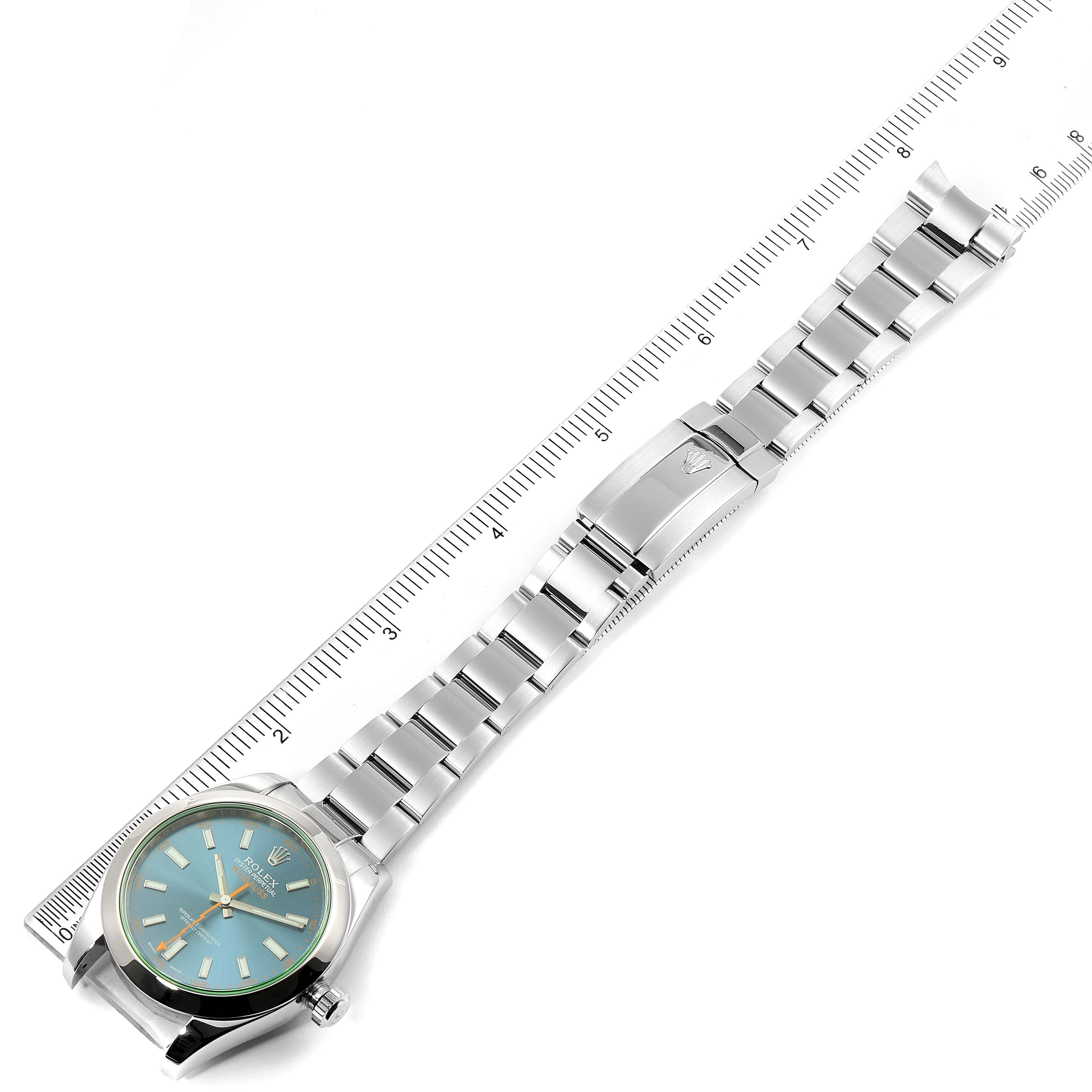 The image shows a Milgauss by Rolex watch from an overhead view, including the face, bracelet, and clasp, aligned with a ruler for scale.