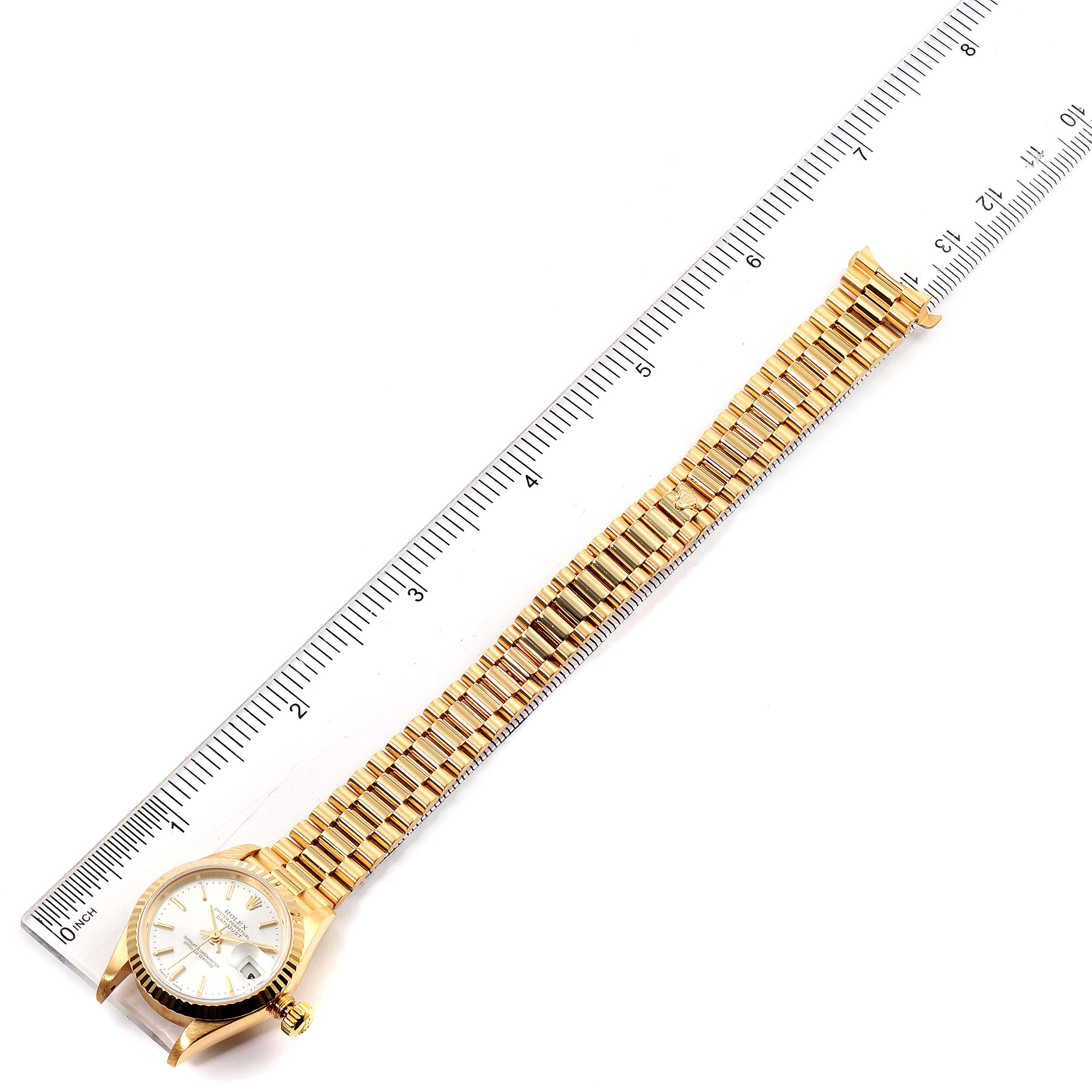 The image shows the full view of a Rolex President 79178 Women's Yellow Gold Silver Dial 79178 Women's Yellow Gold Silver Dial model watch laid flat next to a measuring ruler.