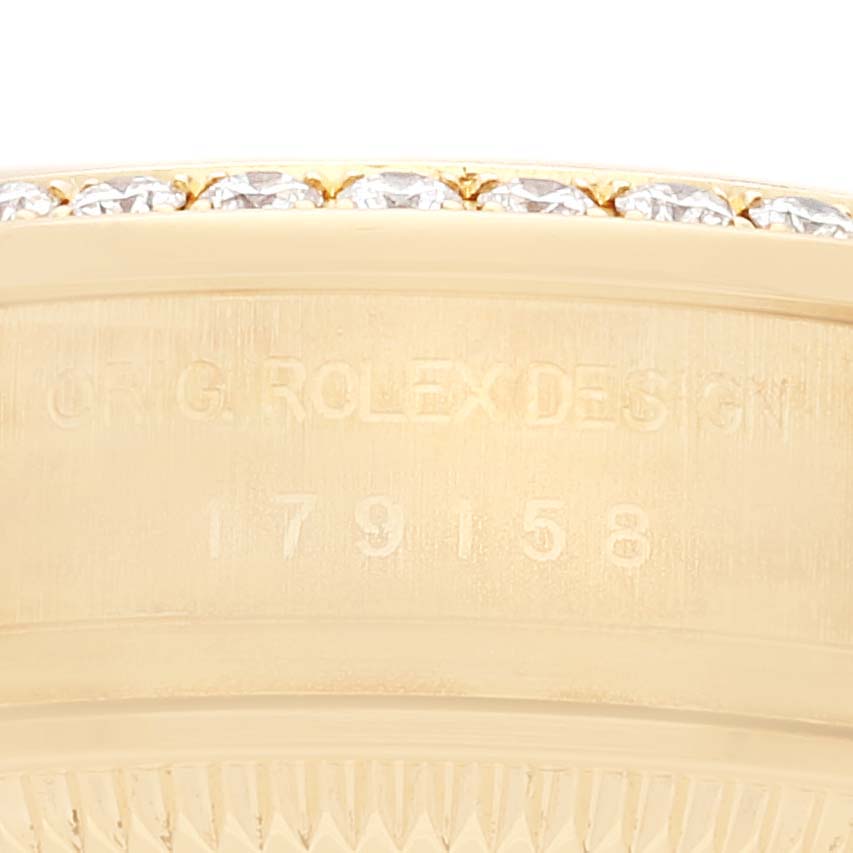 This image shows a close-up of the side of a Rolex President 179158 Women
s Yellow Gold Champagne Dial 179158 Women
s Yellow Gold Champagne Dial model watch, highlighting the engraving and part of the bezel.