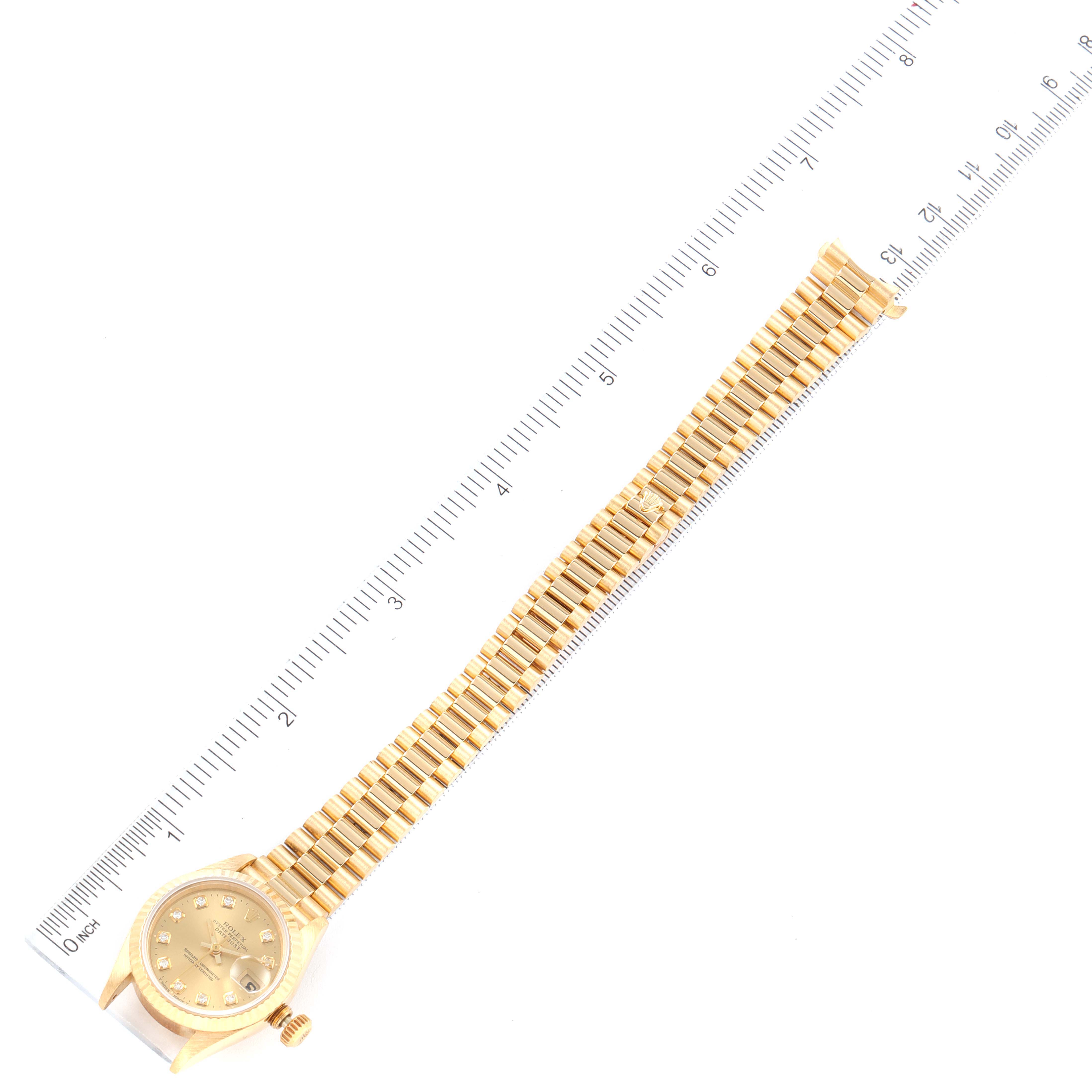 The image shows a top view of a Rolex President 69178 Women
s Yellow Gold Champagne Dial 69178 Women
s Yellow Gold Champagne Dial model watch with its band fully extended alongside a measuring ruler.