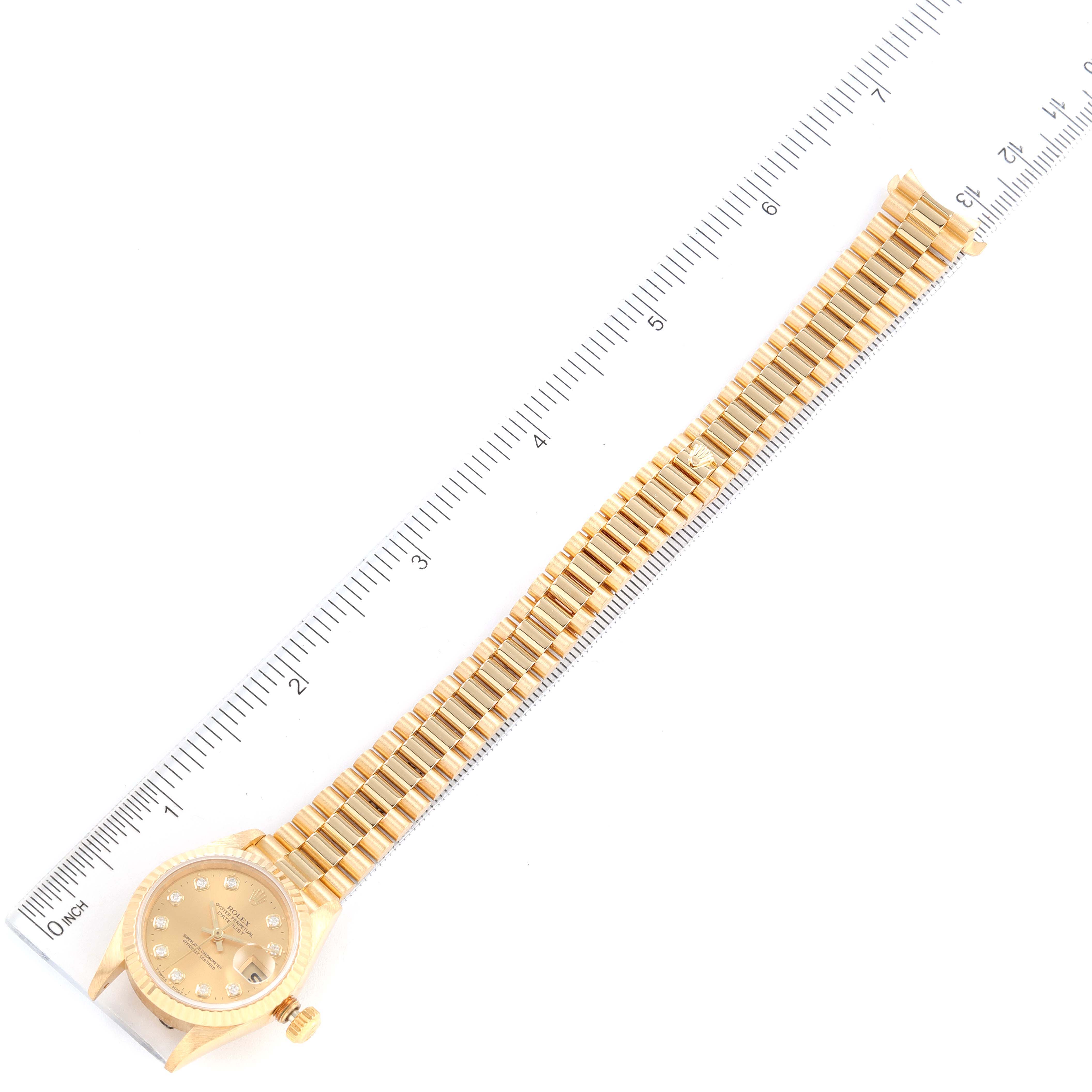 The image shows a top view of a Rolex President 69178 Women
s Yellow Gold Champagne Dial 69178 Women
s Yellow Gold Champagne Dial model watch, displaying its face and entire bracelet alongside a measuring scale.