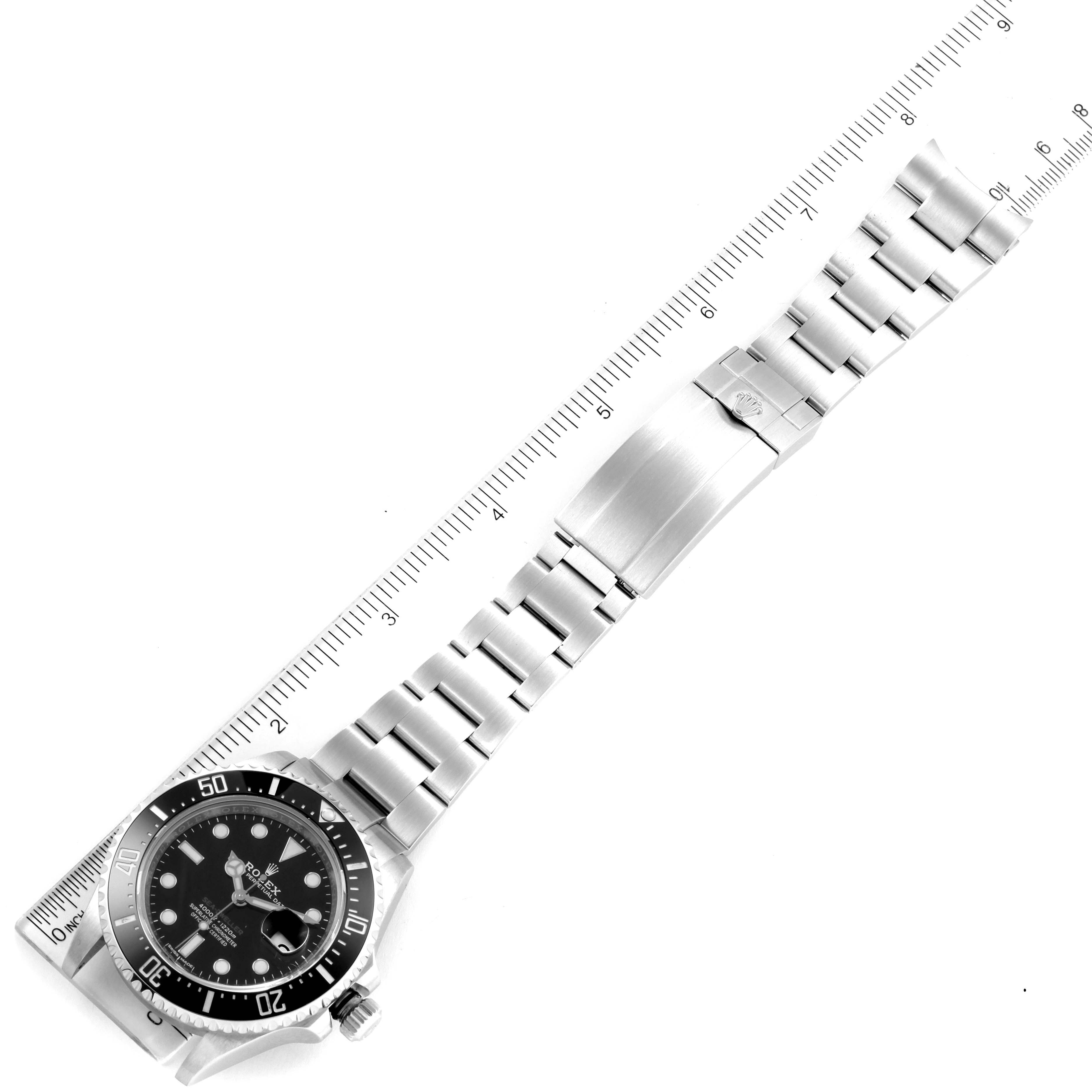 The image shows the Rolex Sea-Dweller 126600 Men
s Stainless Steel Black Dial 126600 Men
s Stainless Steel Black Dial watch laid flat with the bezel, dial, bracelet, and clasp visible next to a ruler for scale.