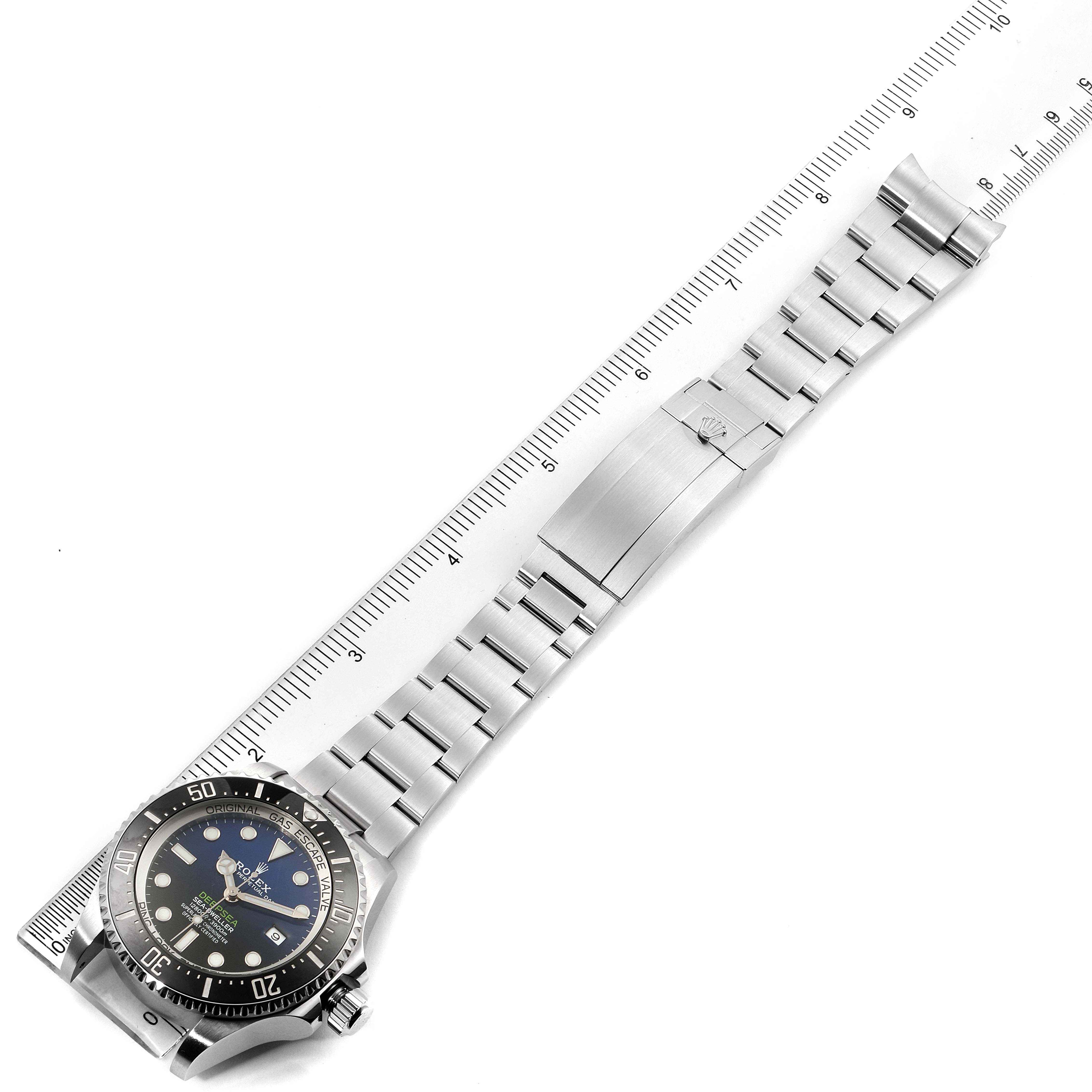 The image shows the Rolex Sea-Dweller 126660 Men's Stainless Steel Blue Dial 126660 Men's Stainless Steel Blue Dial watch laid flat with focus on the face, bracelet, and clasp, alongside a ruler.