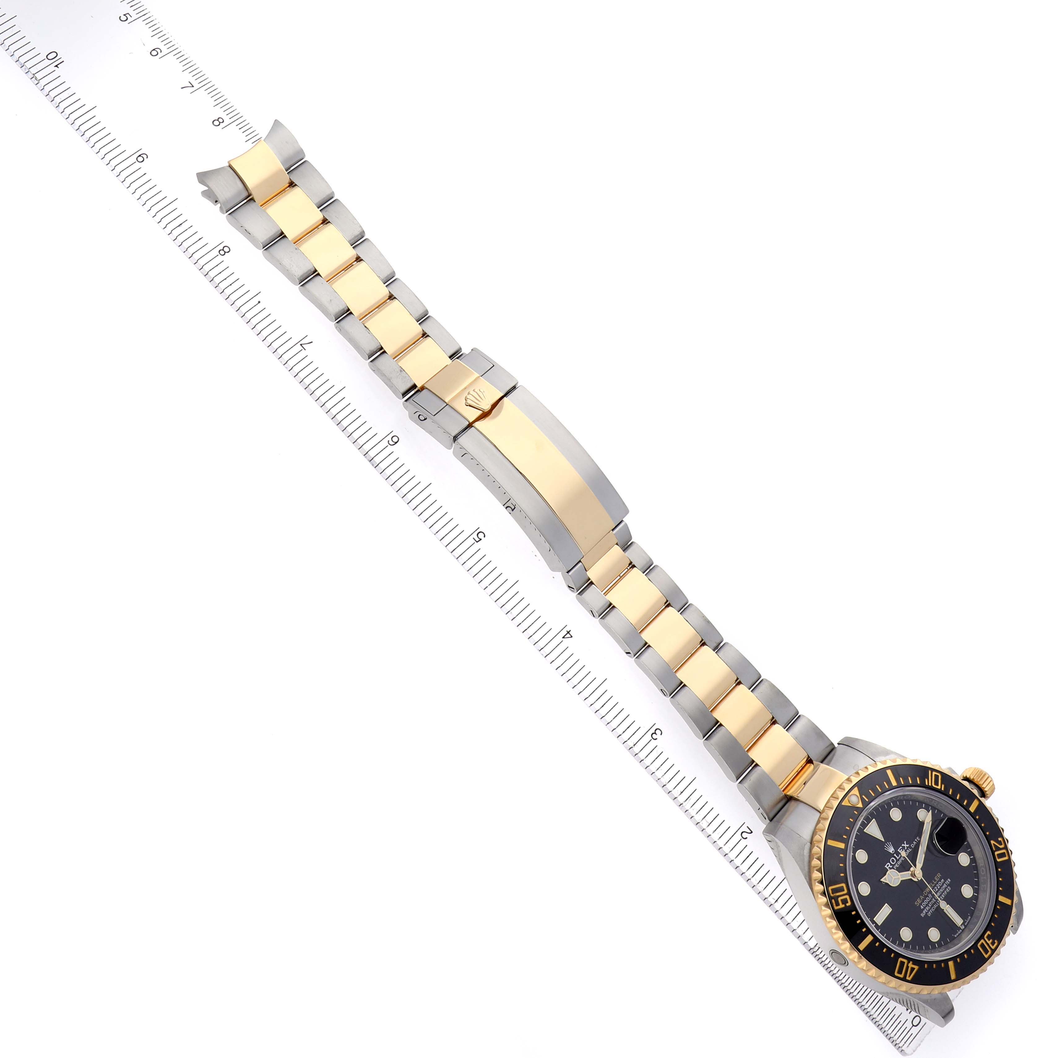 The Rolex Sea-Dweller 126603 Men's Steel and Gold (two tone) Black Dial watch is angled diagonally, showing the face, bezel, bracelet, and clasp alongside a ruler.