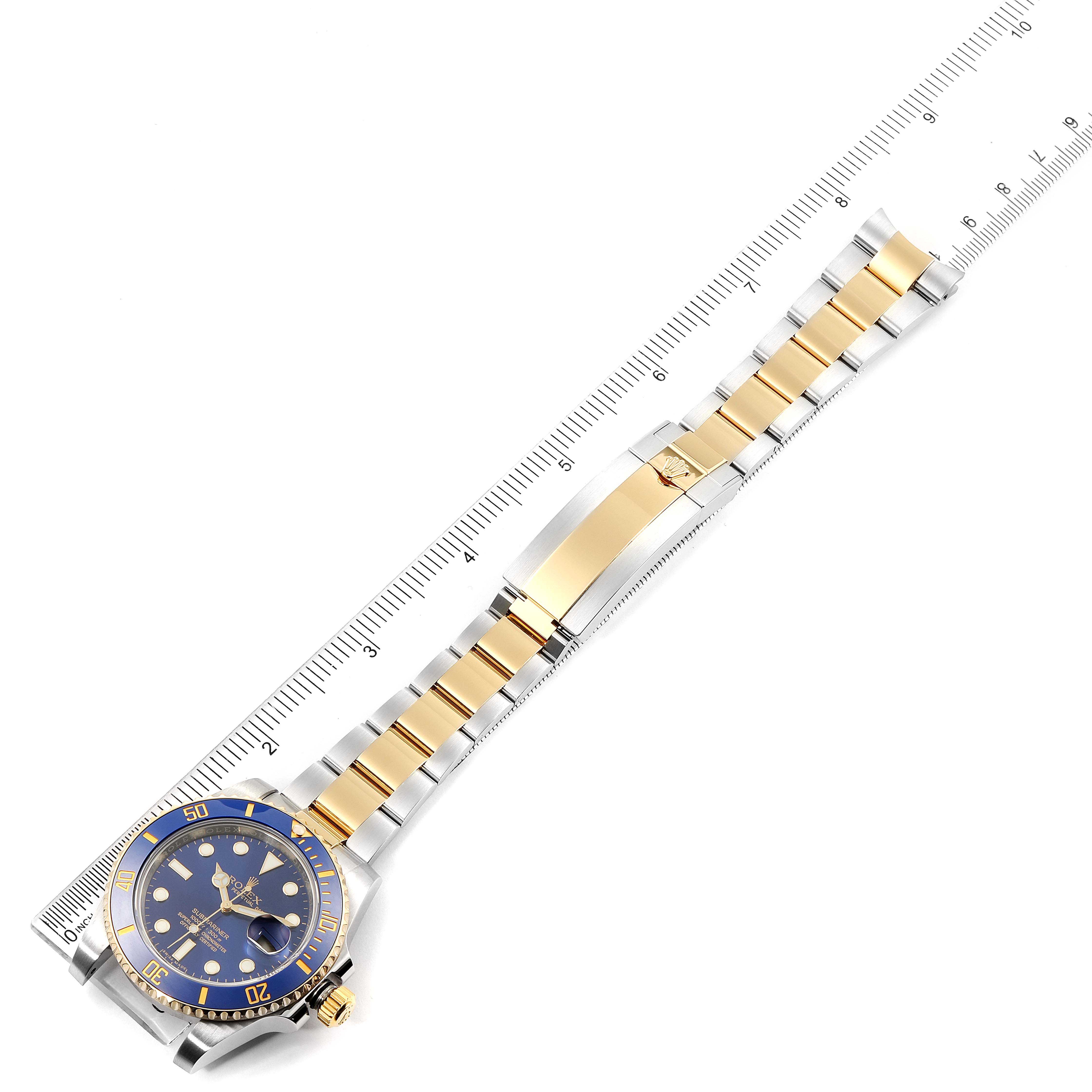 The image shows an overhead view of a Rolex Submariner 116613 Men's Steel and Gold (two tone) Blue Dial 116613 Men's Steel and Gold (two tone) Blue Dial watch, featuring its blue dial, gold bezel, and two-tone bracelet.