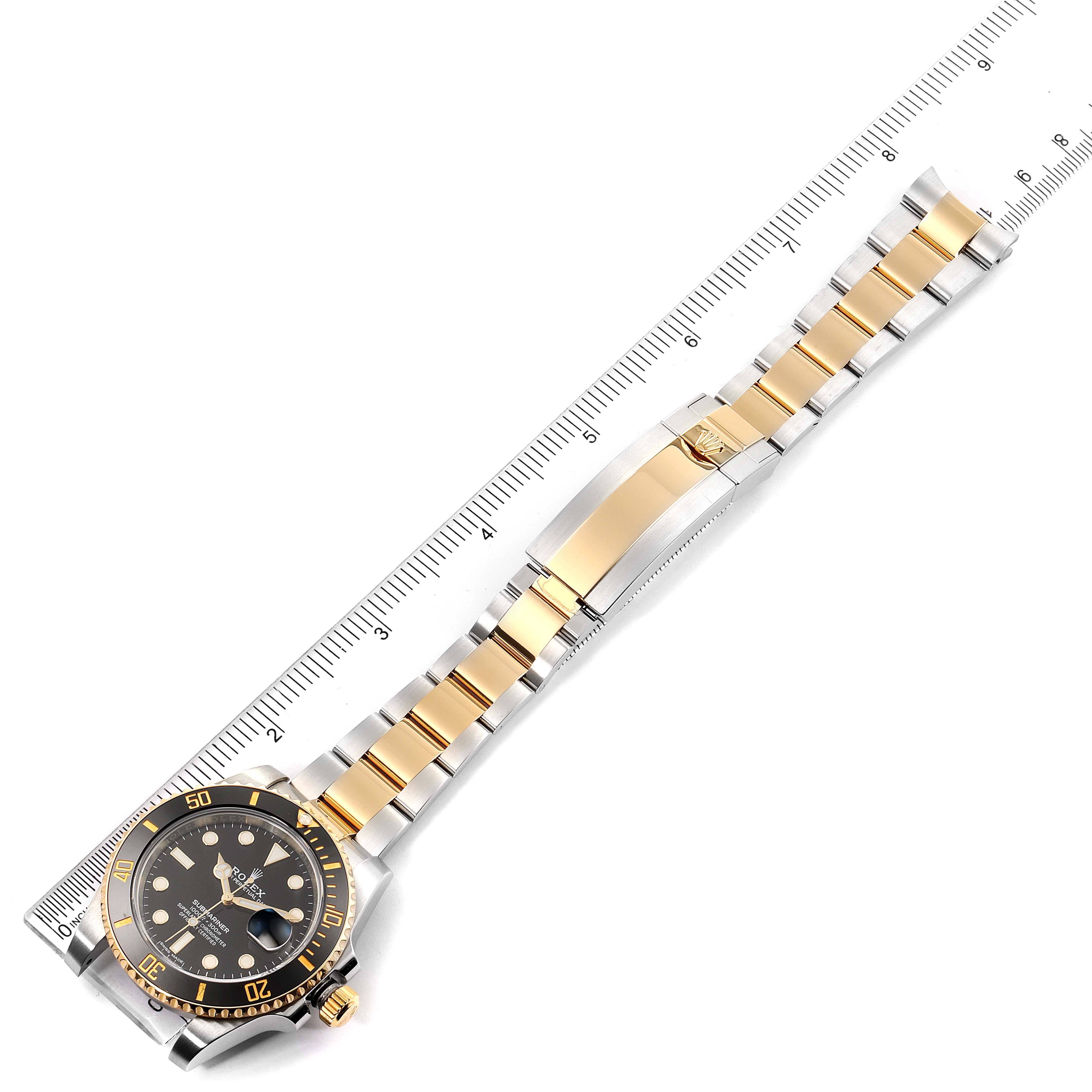 The image shows a Rolex Submariner 116613 Men's Steel and Gold (two tone) Black Dial 116613 Men's Steel and Gold (two tone) Black Dial watch from a top-down angle, highlighting the bracelet and face alongside a measuring ruler.