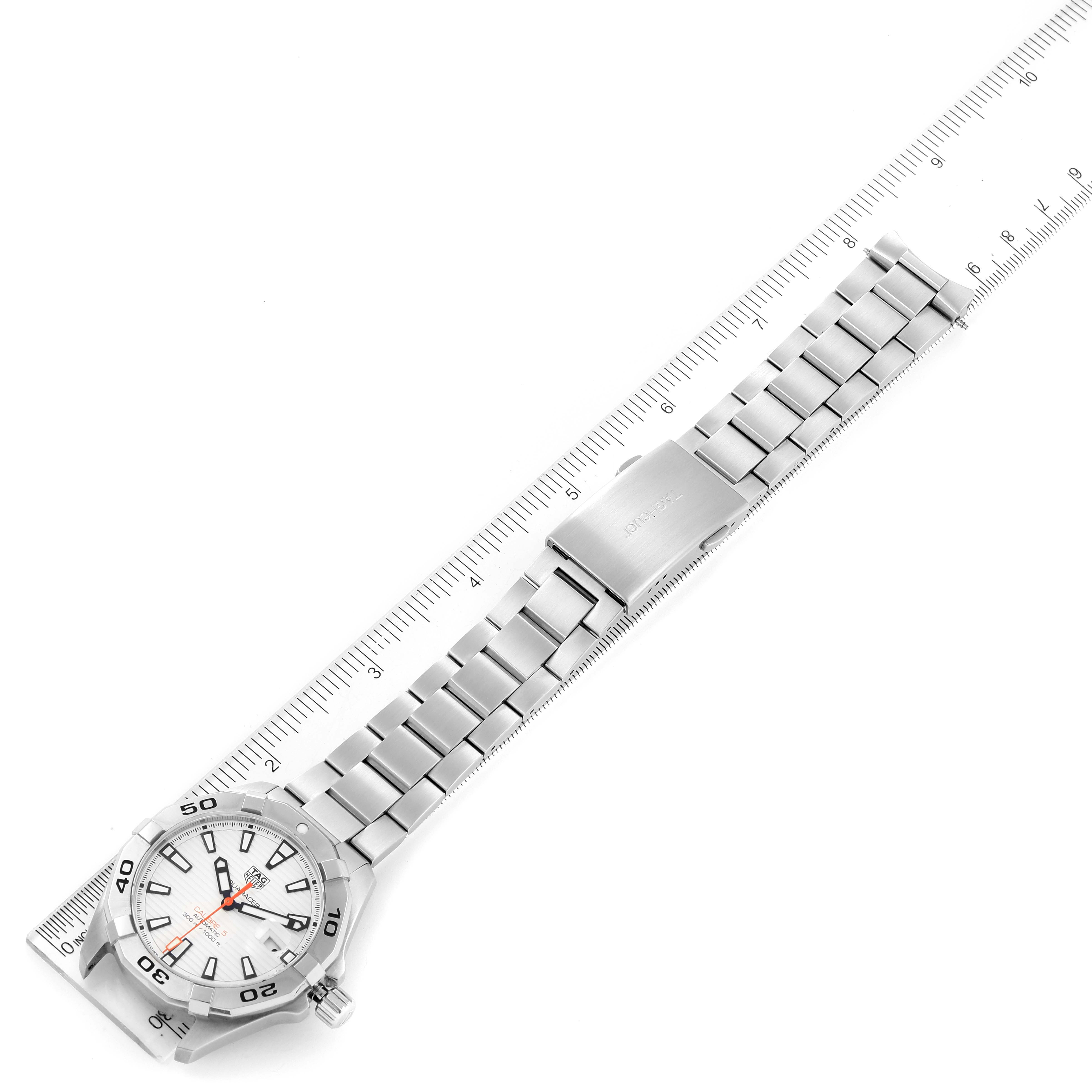 The image shows a Tag Heuer Aquaracer WBD2111.BA0928 Men's Stainless Steel White Dial WBD2111.BA0928 Men's Stainless Steel White Dial watch laid flat on a ruler, displaying its face and full metal bracelet.