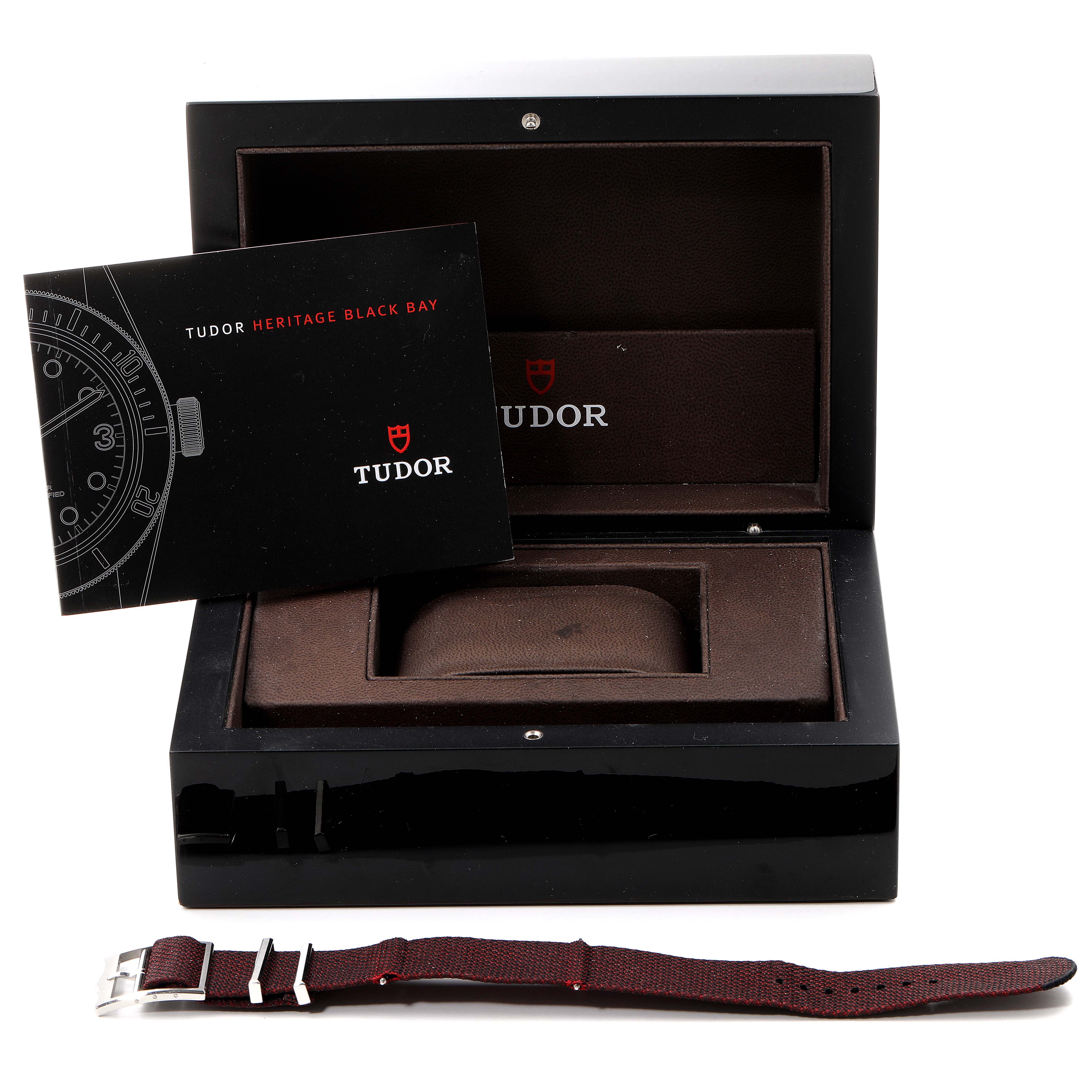 The image shows an open Tudor Heritage Black Bay 79230R Men
s Stainless Steel Black Dial 79230R Men
s Stainless Steel Black Dial watch box with an instruction manual and an additional strap in front.