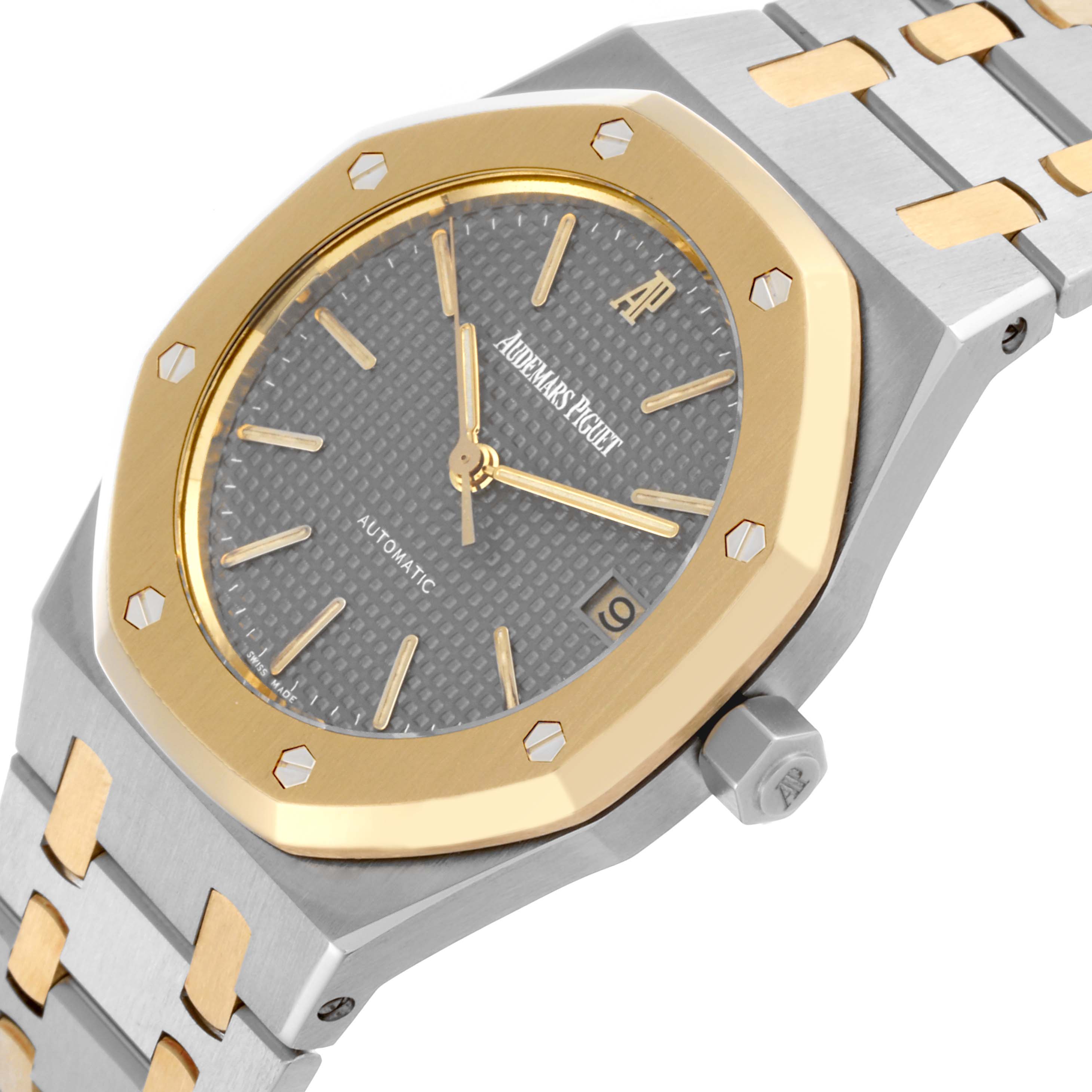 The image shows a close-up of the Audemars Piguet Royal Oak 14790SA.OO.0789SA.01 Men's Steel and Gold (two tone) Grey Dial 14790SA.OO.0789SA.01 Men's Steel and Gold (two tone) Grey Dial's face, bezel, crown, and part of the bracelet from a side angle.