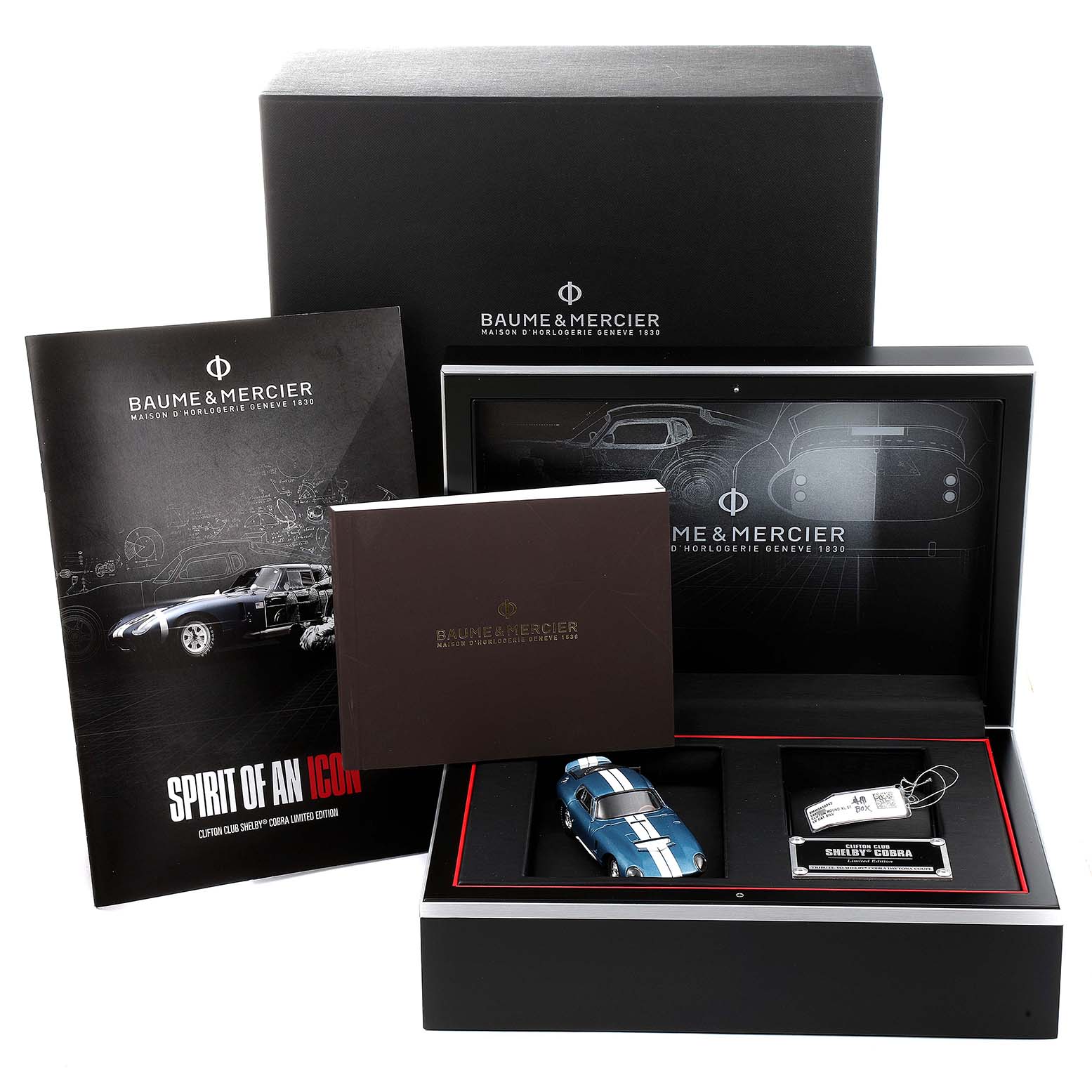 The image shows the packaging and accessories for the Baume & Mercier Clifton M0A10342 Men's Stainless Steel Silver Dial M0A10342 Men's Stainless Steel Silver Dial model, including a booklet, collector's box, and a model car.