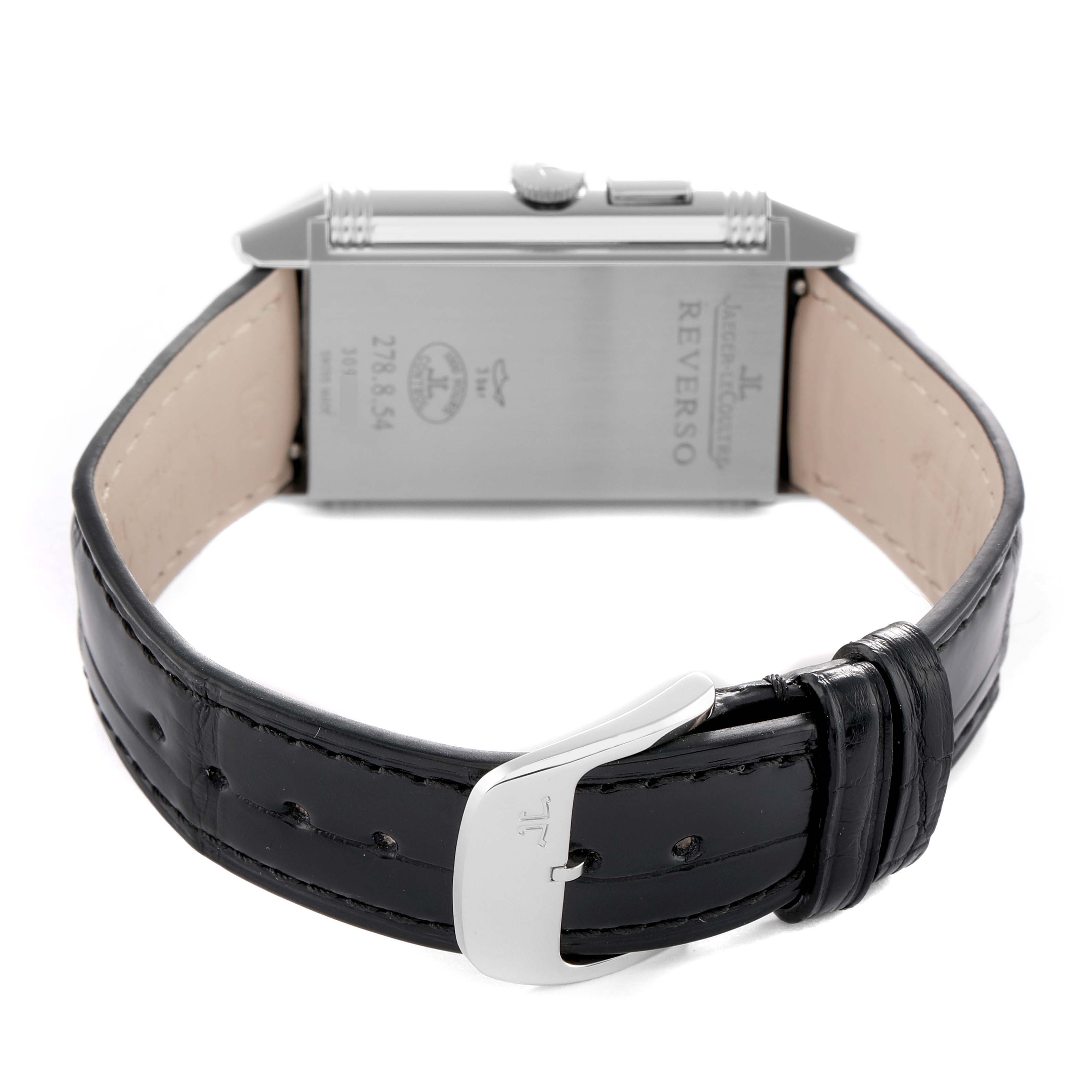 The Jaeger-LeCoultre Reverso watch is shown from a rear angle, highlighting the case back, crown, and leather strap with buckle.