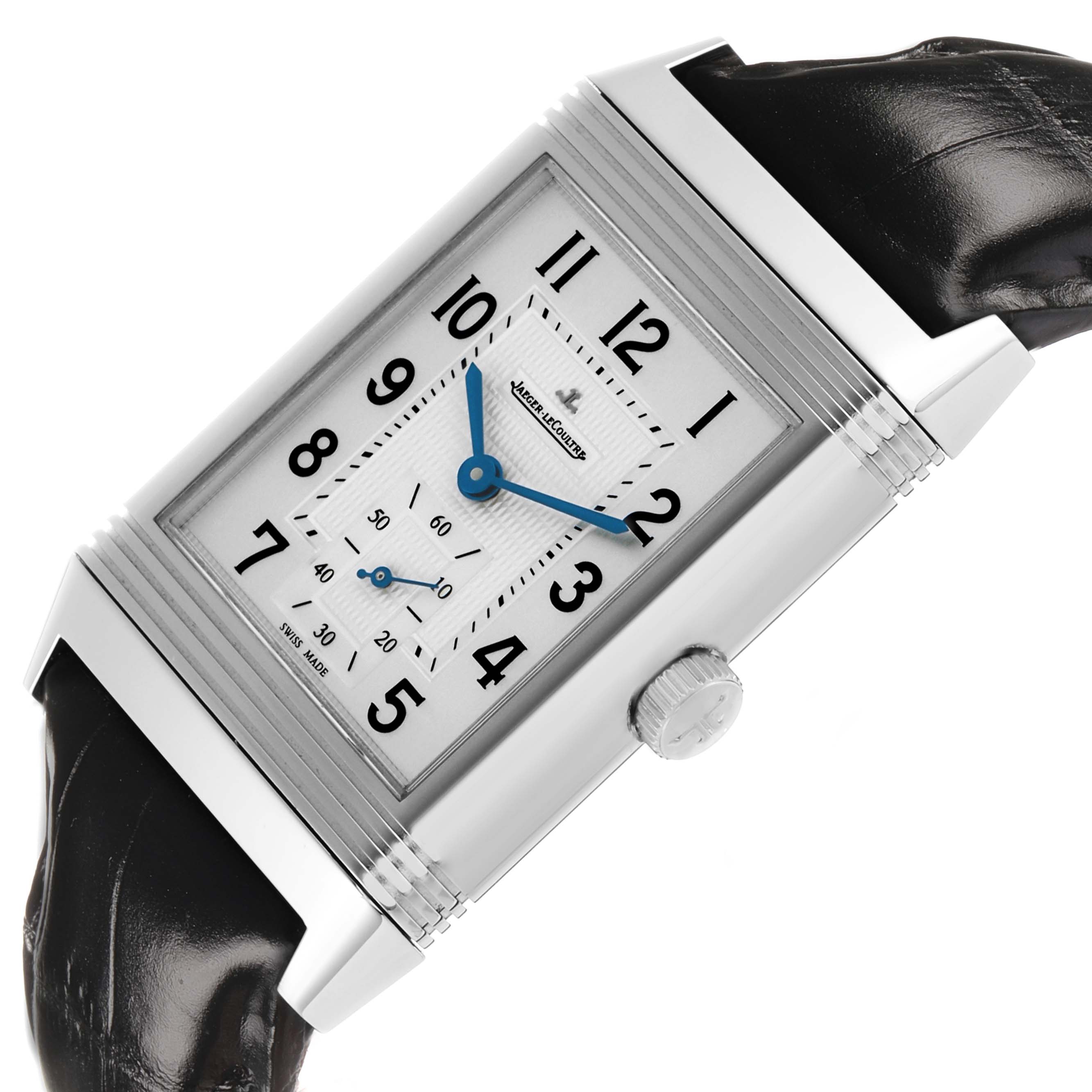The Jaeger-LeCoultre Reverso watch is shown at an angle displaying the dial, crown, and leather strap.