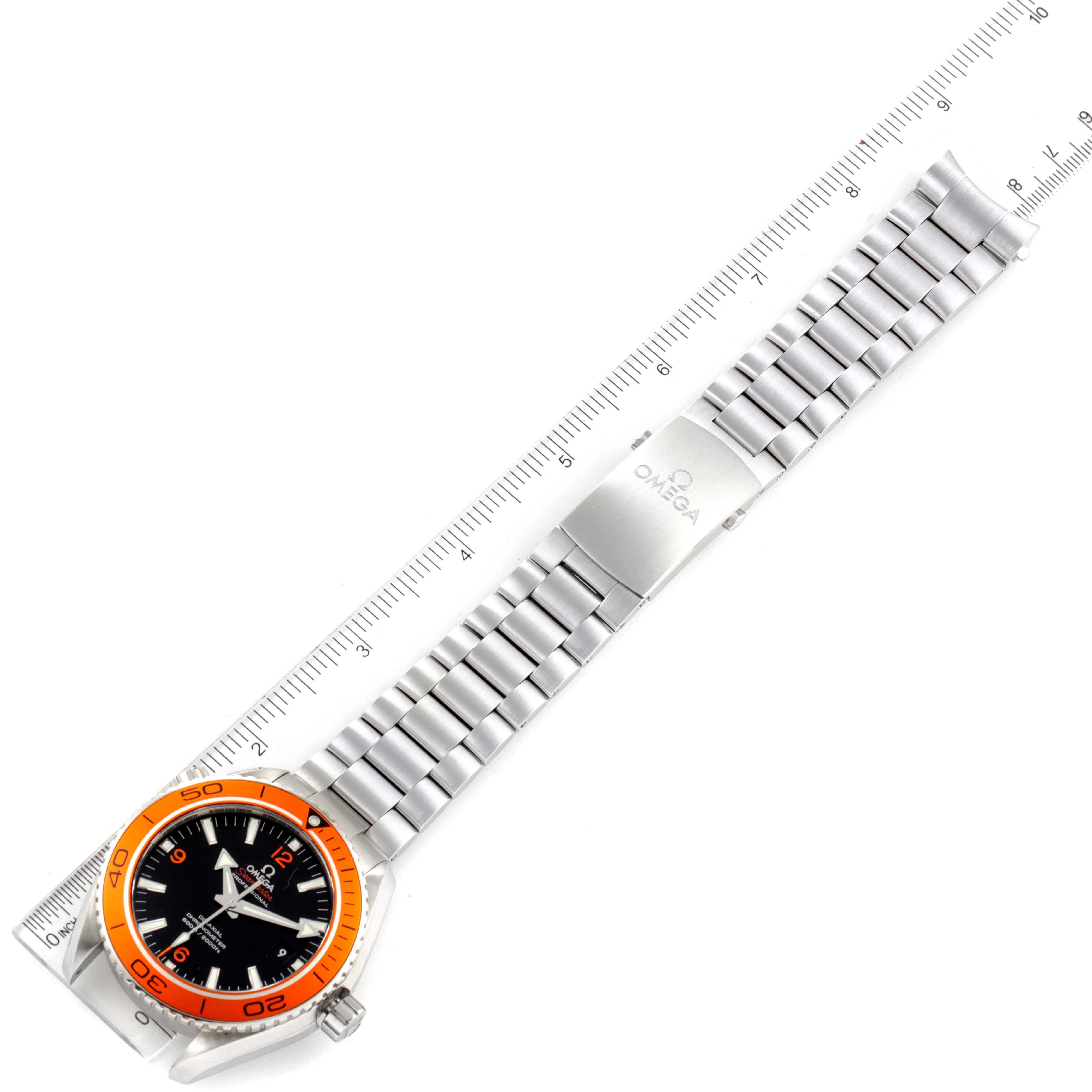 The image shows an overhead view of an Omega Planet Ocean 232.30.46.21.01.002 Men's Stainless Steel Black Dial 232.30.46.21.01.002 Men's Stainless Steel Black Dial watch with a stainless steel band against a measuring ruler.