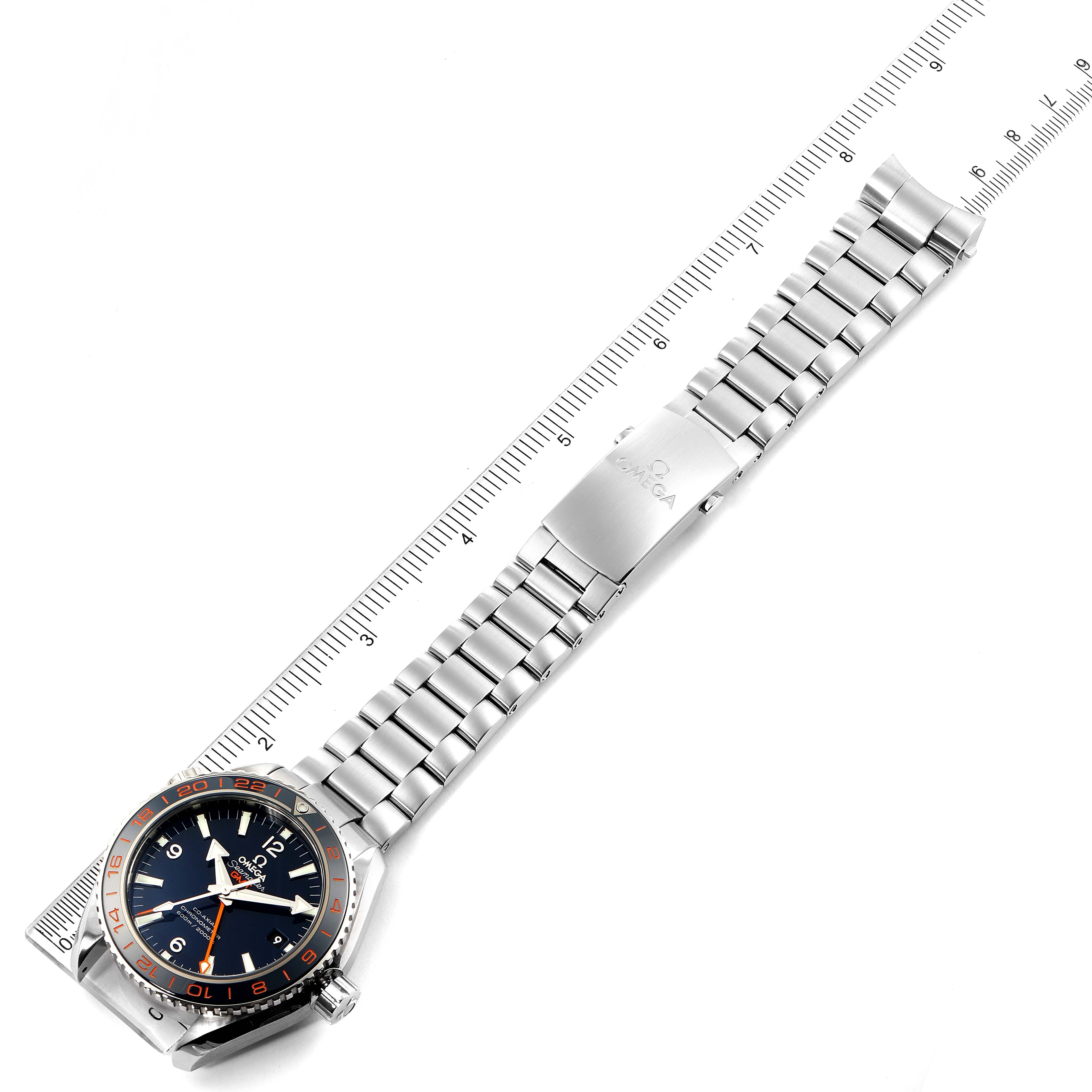 The image shows an Omega Planet Ocean 232.30.44.22.03.001 Men
s Stainless Steel Blue Dial 232.30.44.22.03.001 Men
s Stainless Steel Blue Dial watch laid flat, displaying the face, stainless steel bracelet, and clasp, alongside a ruler.