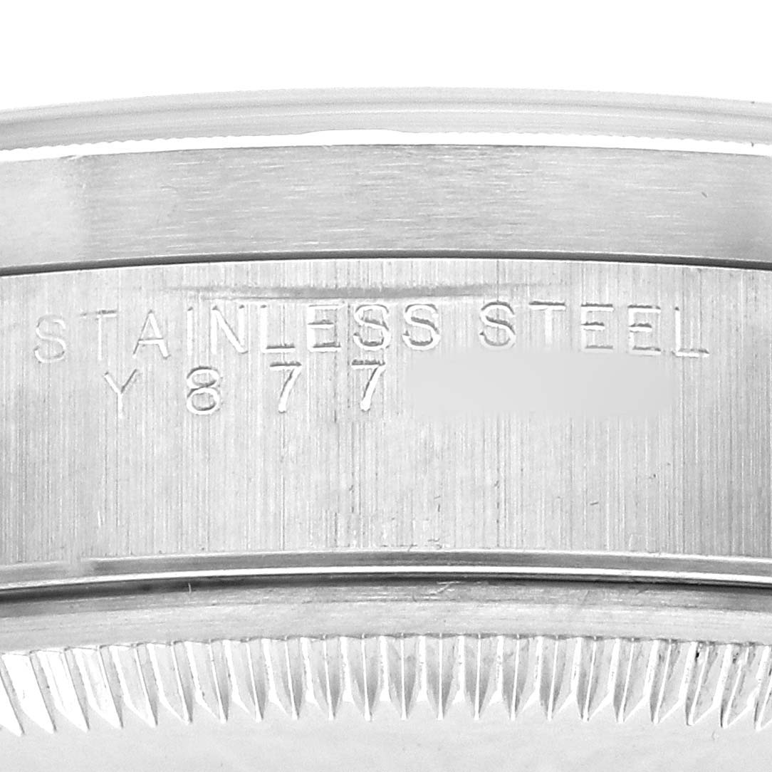 The image shows a close-up of the side of a Rolex Date 15210 Men's Stainless Steel Blue Dial watch case, highlighting the engraved stainless steel marking.