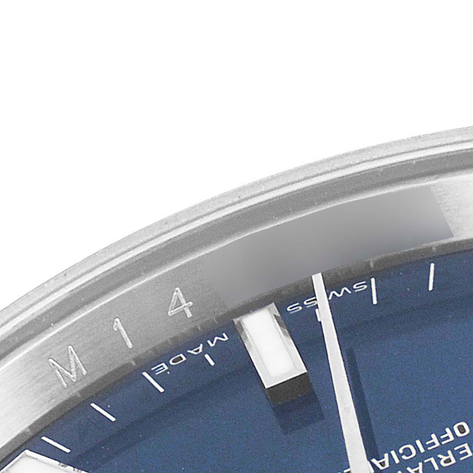 The image shows a close-up of the face and bezel of a Rolex Date 115210 Men's Stainless Steel Blue Dial 115210 Men's Stainless Steel Blue Dial model watch.