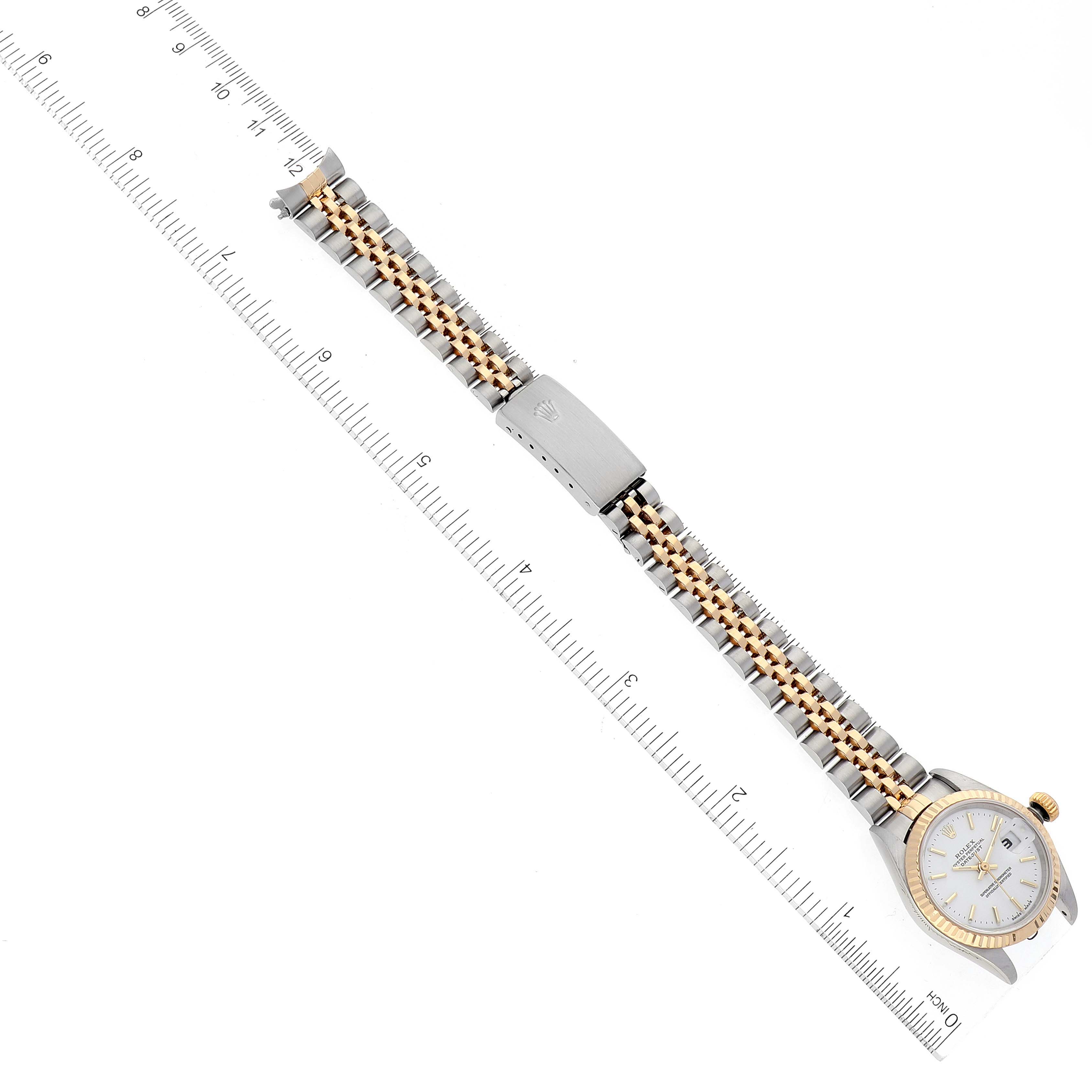 This image shows a Rolex Datejust 79173 Women's Steel and Gold (two tone) White Dial 79173 Women's Steel and Gold (two tone) White Dial watch laid flat with a two-tone bracelet and a silver dial next to a ruler for scale.