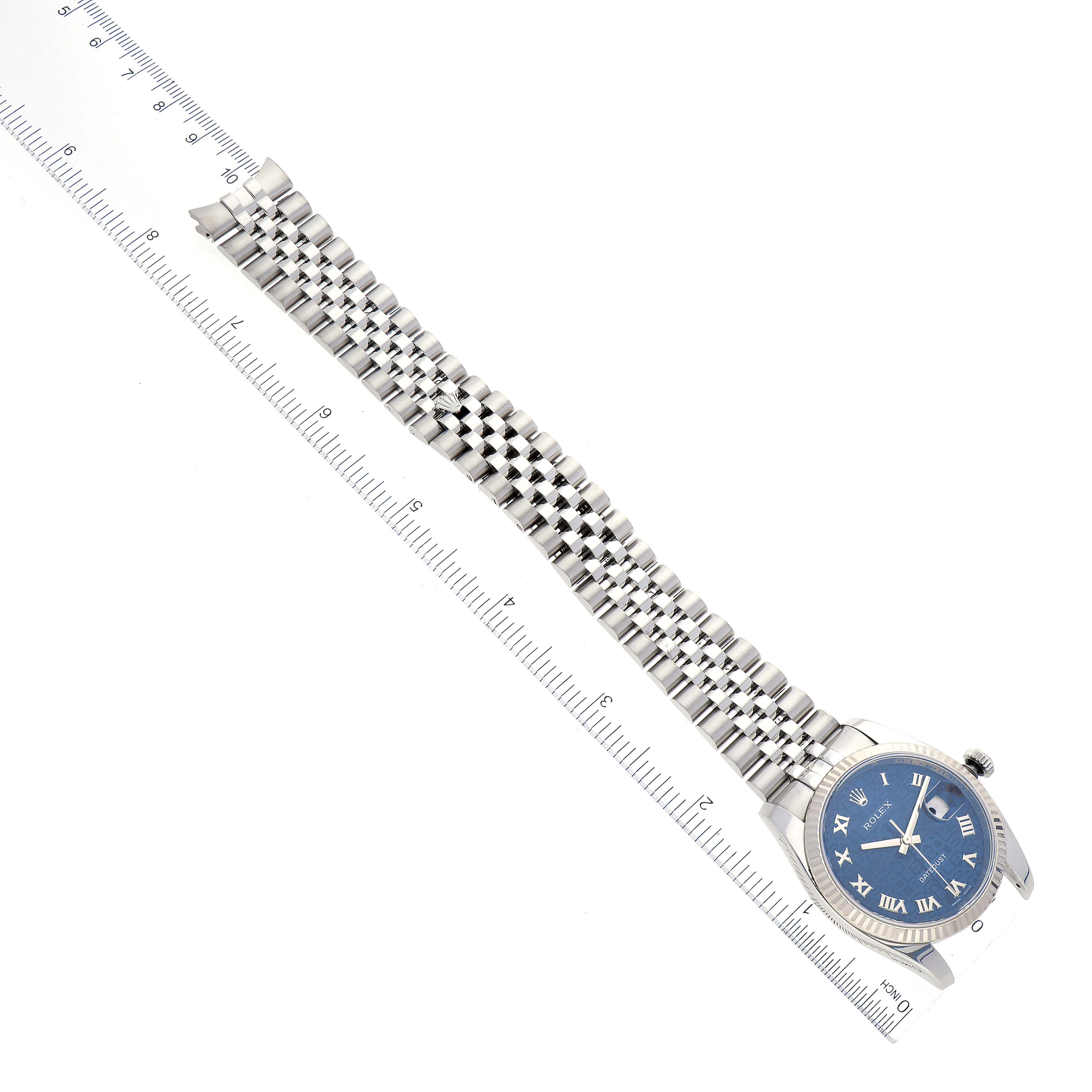The image shows a Rolex Datejust 116234 Men's Stainless Steel Blue Dial 116234 Men's Stainless Steel Blue Dial watch laid flat with its blue dial and link bracelet fully visible, alongside a ruler for scale.