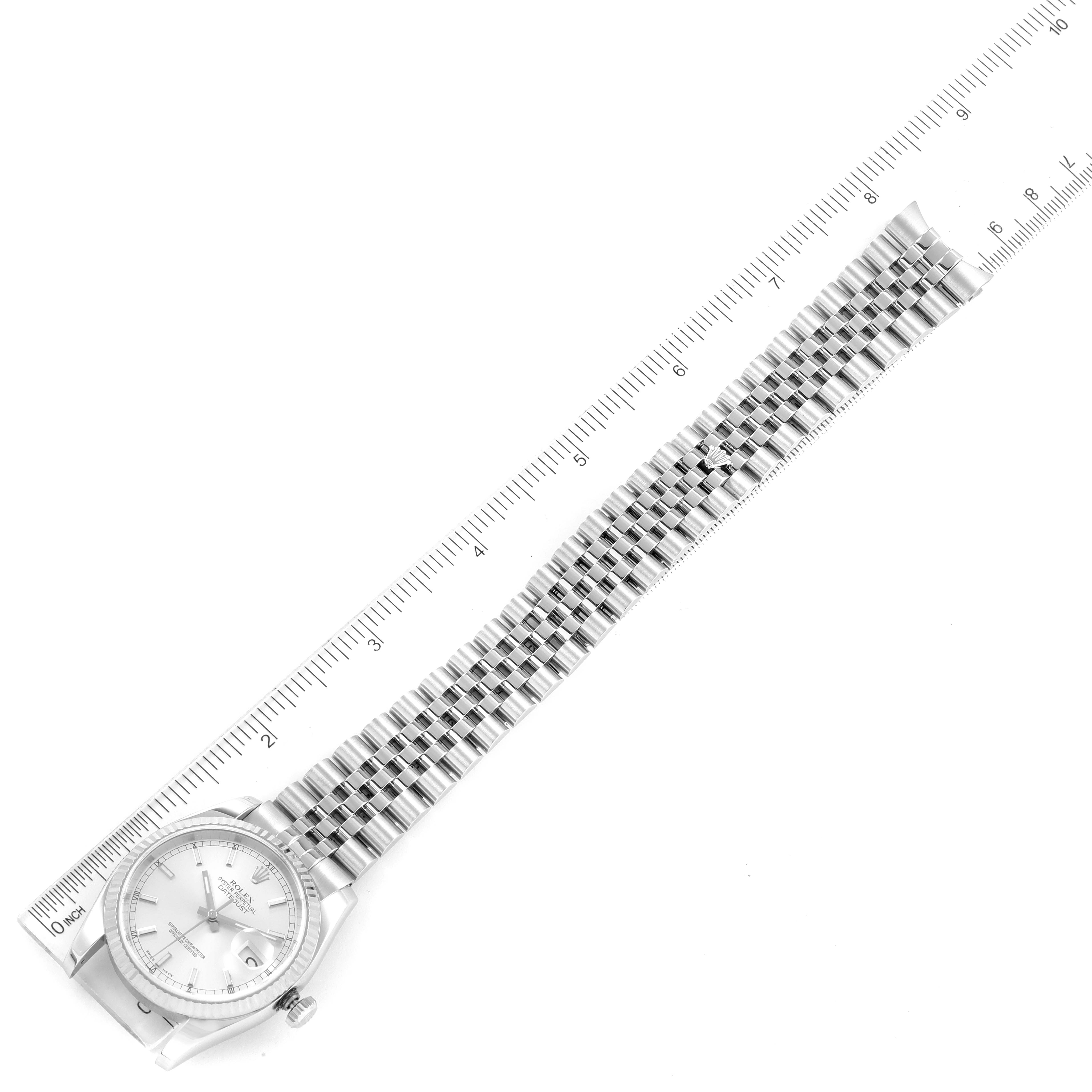 This image shows a Rolex Datejust 116234 Men
s Stainless Steel Silver Dial 116234 Men
s Stainless Steel Silver Dial watch laid flat alongside a ruler, highlighting its face, bezel, case, and bracelet.