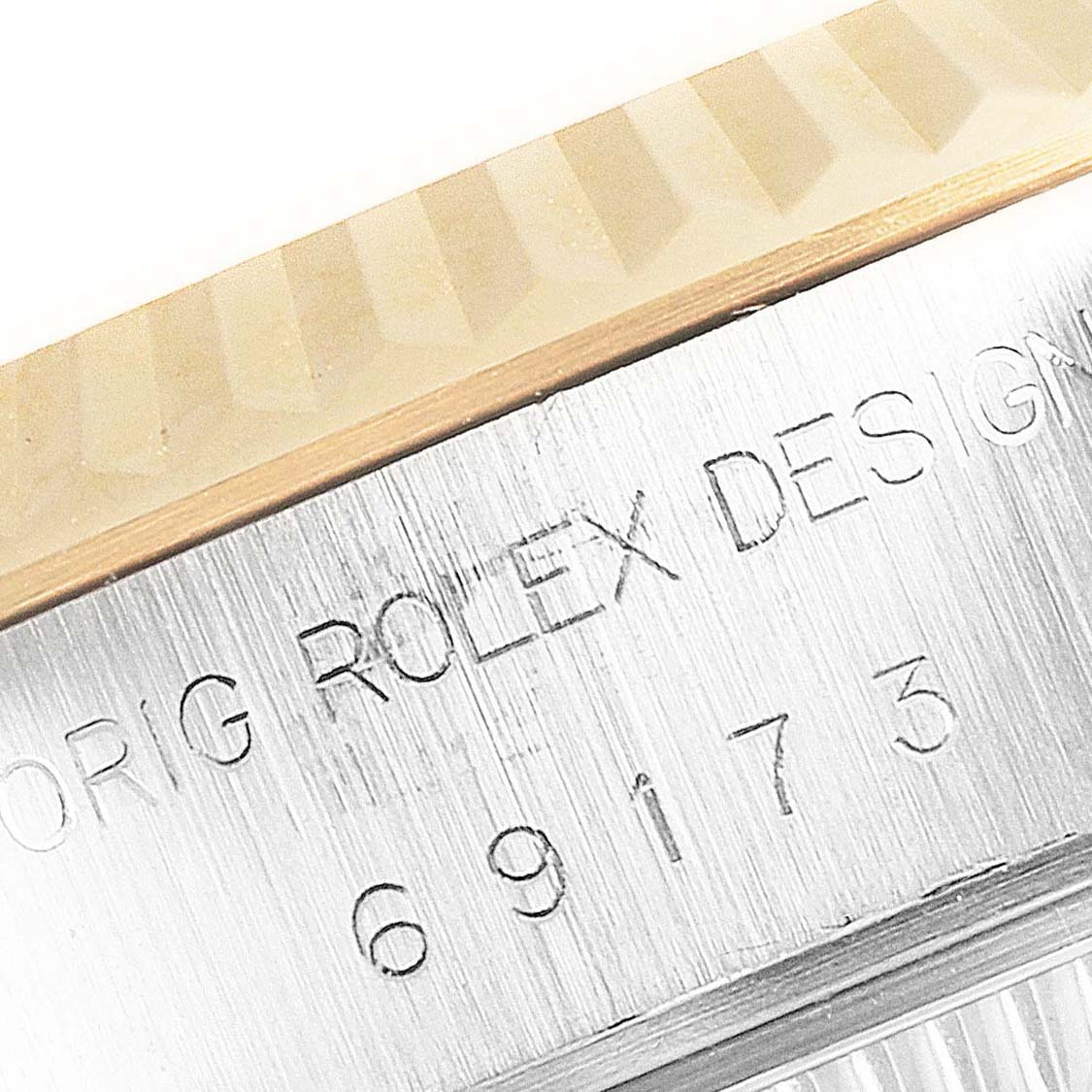 This close-up image of the Rolex Datejust 69173 Women
s Steel and Gold (two tone) Silver Dial 69173 Women
s Steel and Gold (two tone) Silver Dial shows the fluted bezel and part of the engraved text and serial number.