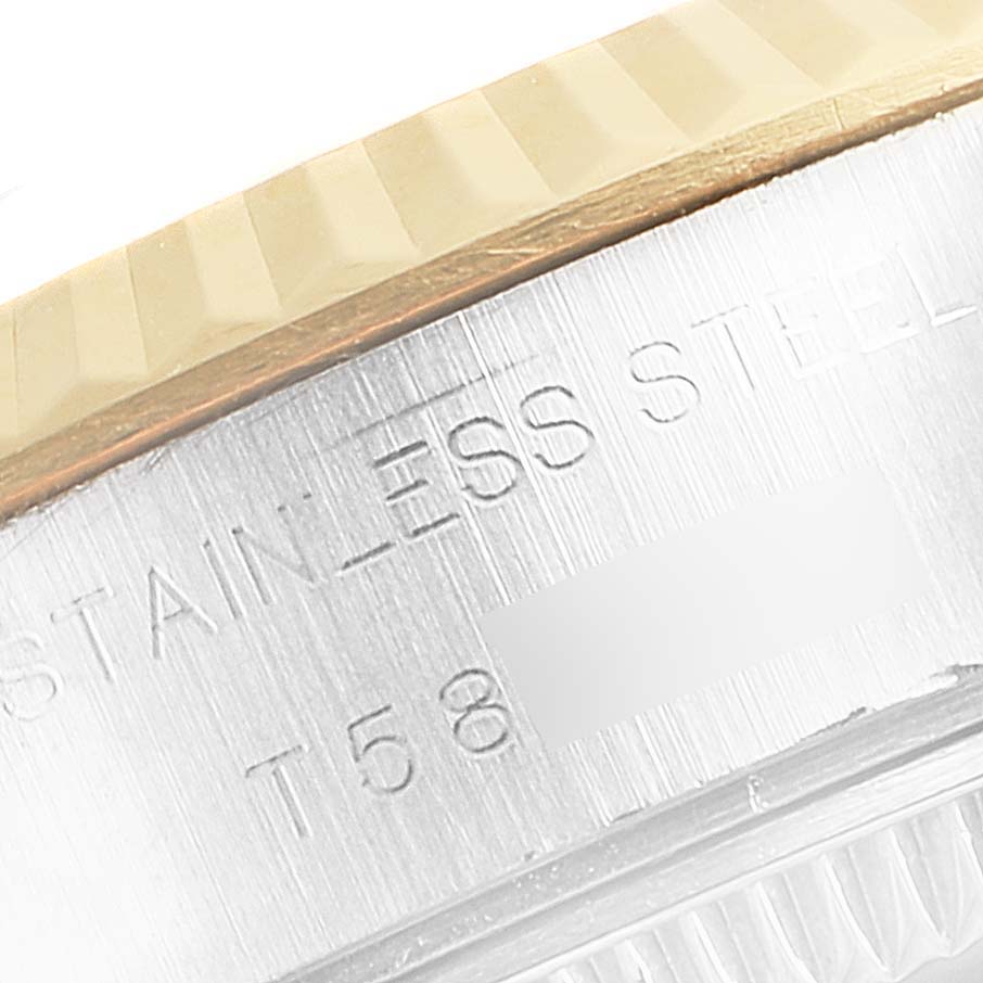 This close-up image of the Rolex Datejust 69173 Women
s Steel and Gold (two tone) Silver Dial 69173 Women
s Steel and Gold (two tone) Silver Dial watch shows part of the bezel and the stainless steel case with engraved text.