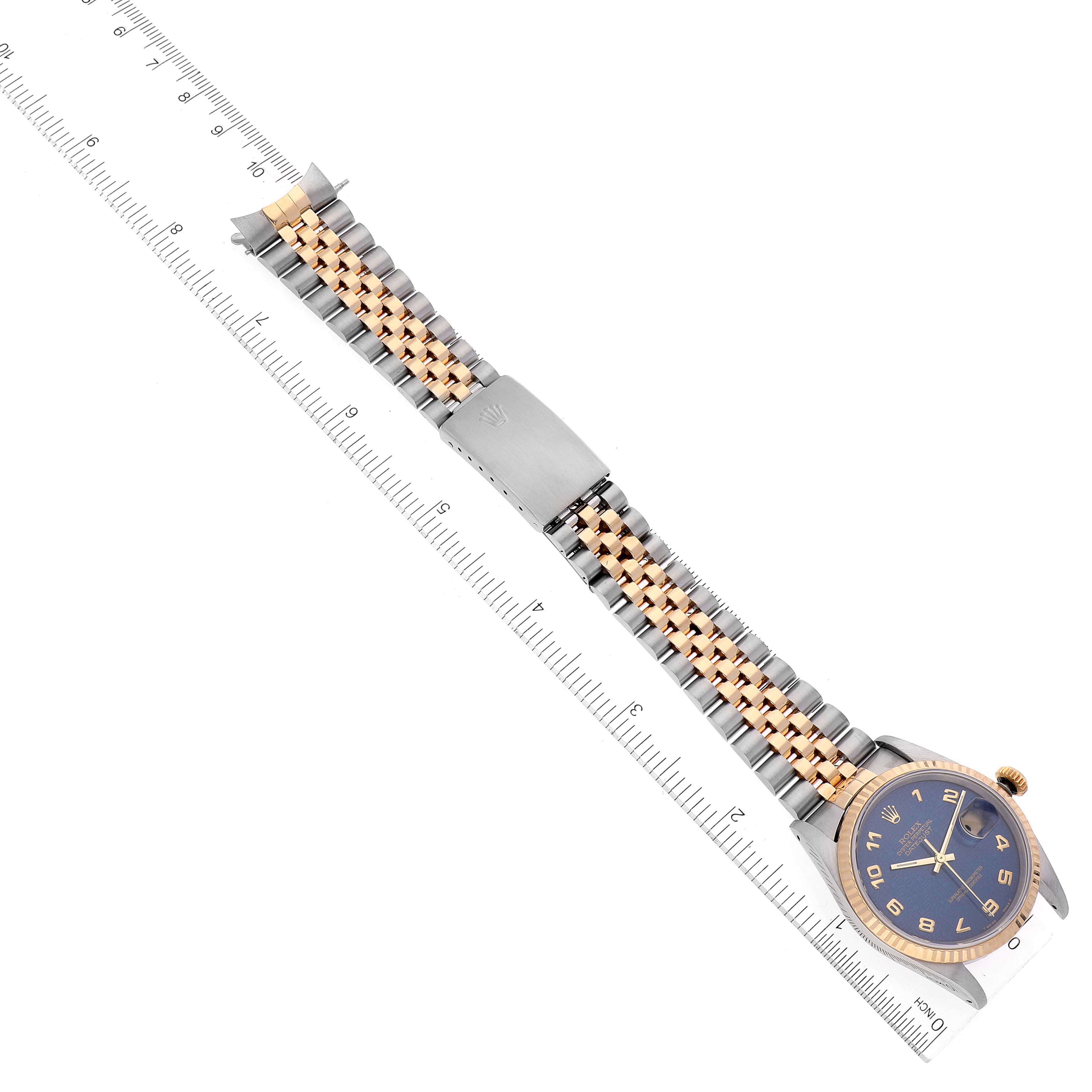 The image shows a Rolex Datejust 16233 Men's Steel and Gold (two tone) Blue Dial 16233 Men's Steel and Gold (two tone) Blue Dial watch laid flat with the face and bracelet visible, alongside a ruler for scale.