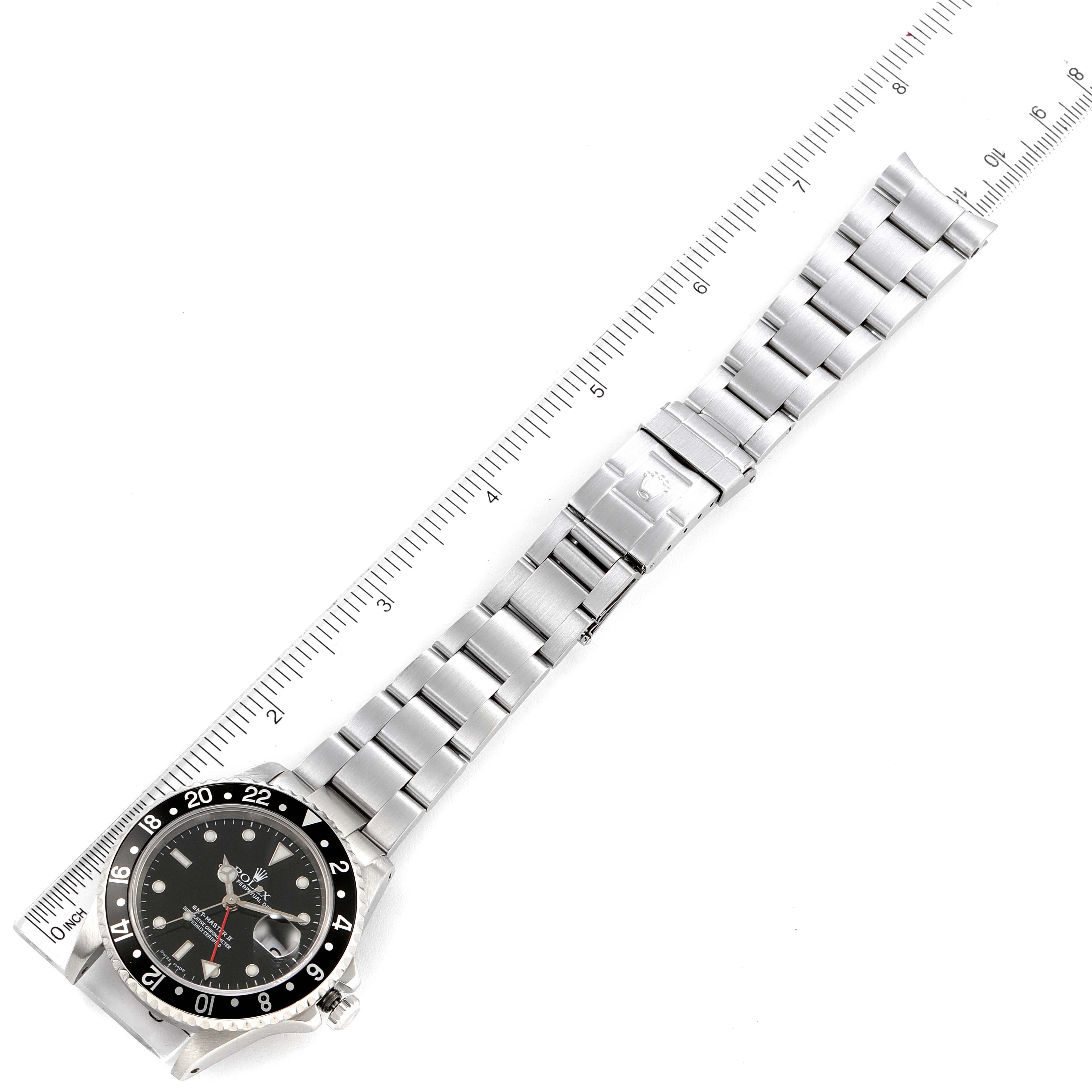 A top-down view showing the Rolex GMT-Master 16710 Men
s Stainless Steel Black Dial 16710 Men
s Stainless Steel Black Dial watch, including its face, bezel, and fully extended metal bracelet alongside a measuring ruler.