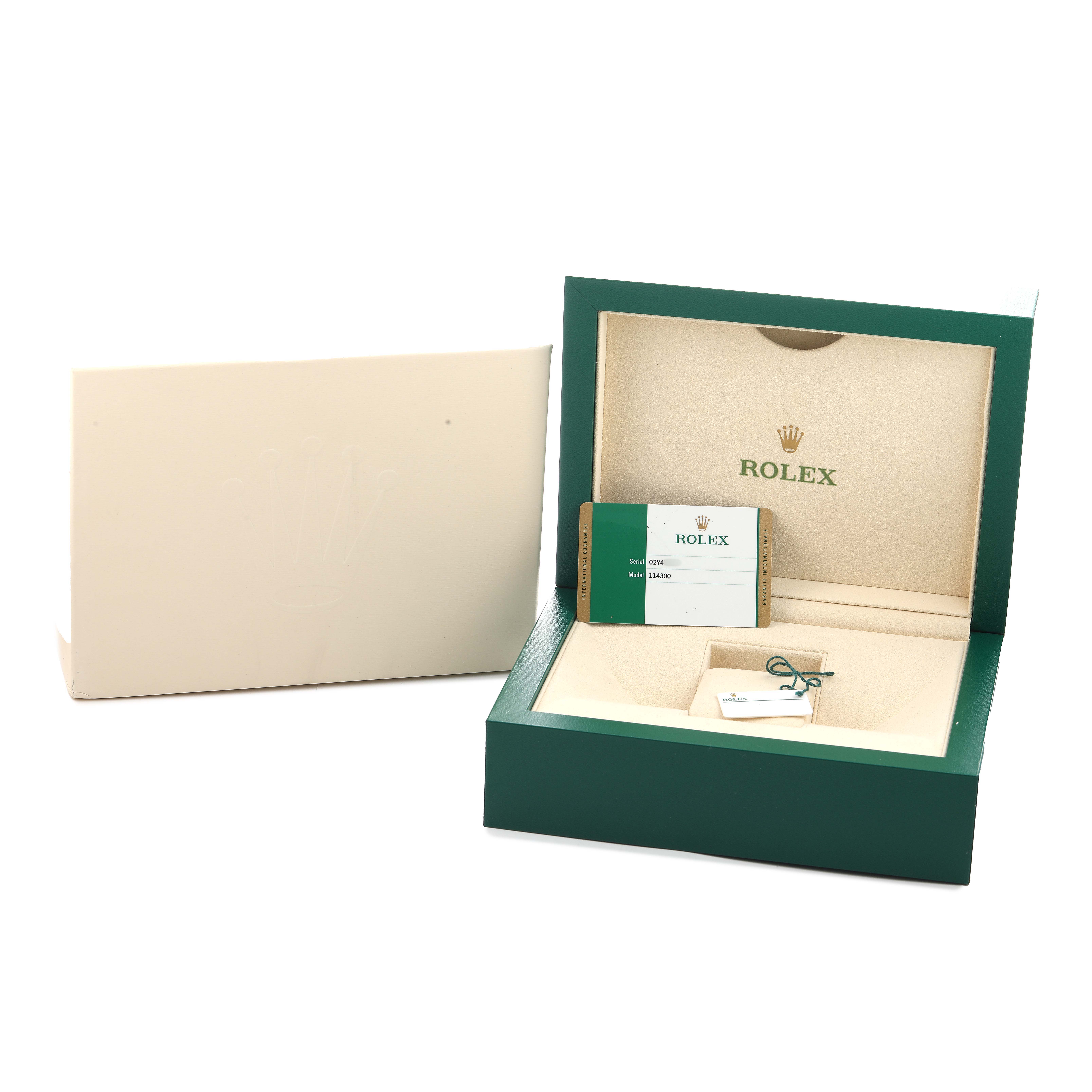 The image shows an open Rolex Oyster Perpetual 114300 Men's Stainless Steel Grey Dial box with warranty cards and tags displayed inside.