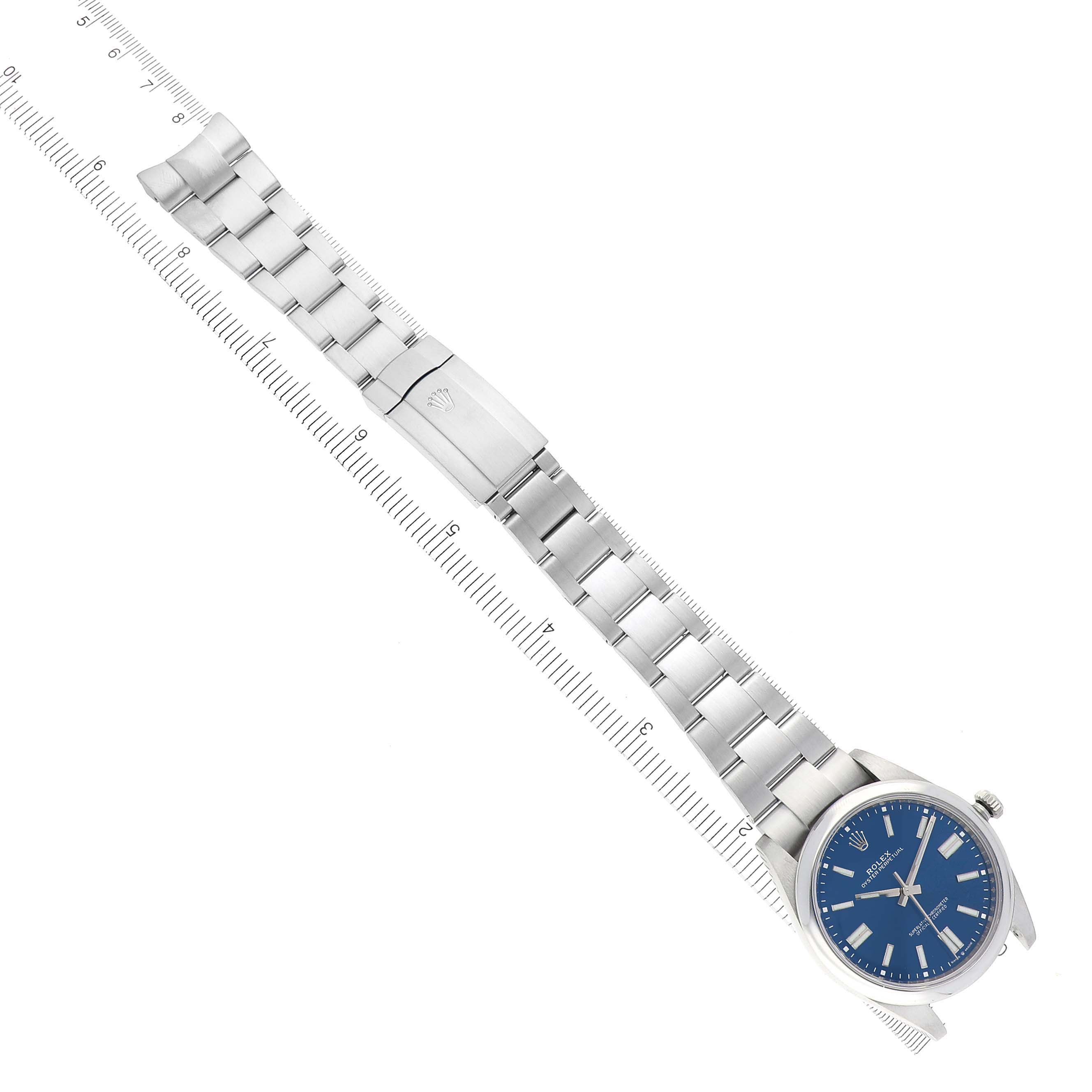 The Oyster Perpetual Rolex watch is shown from a top-down angle displaying its full bracelet and clasp.