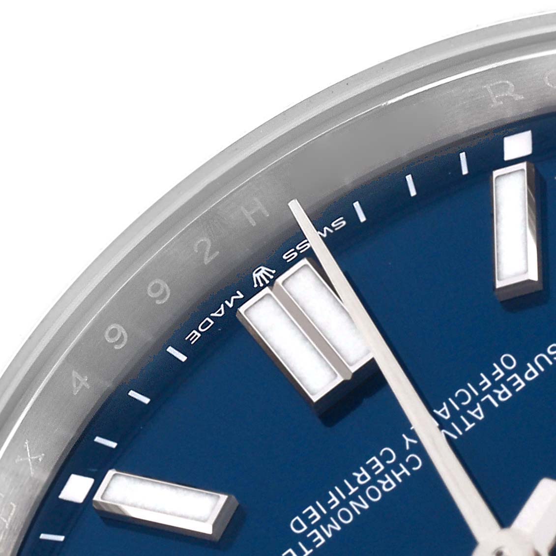 The image shows a close-up of the Rolex Oyster Perpetual 124300 Men's Stainless Steel Blue Dial 124300 Men's Stainless Steel Blue Dial's dial, highlighting the hour markers, hands, and part of the bezel.