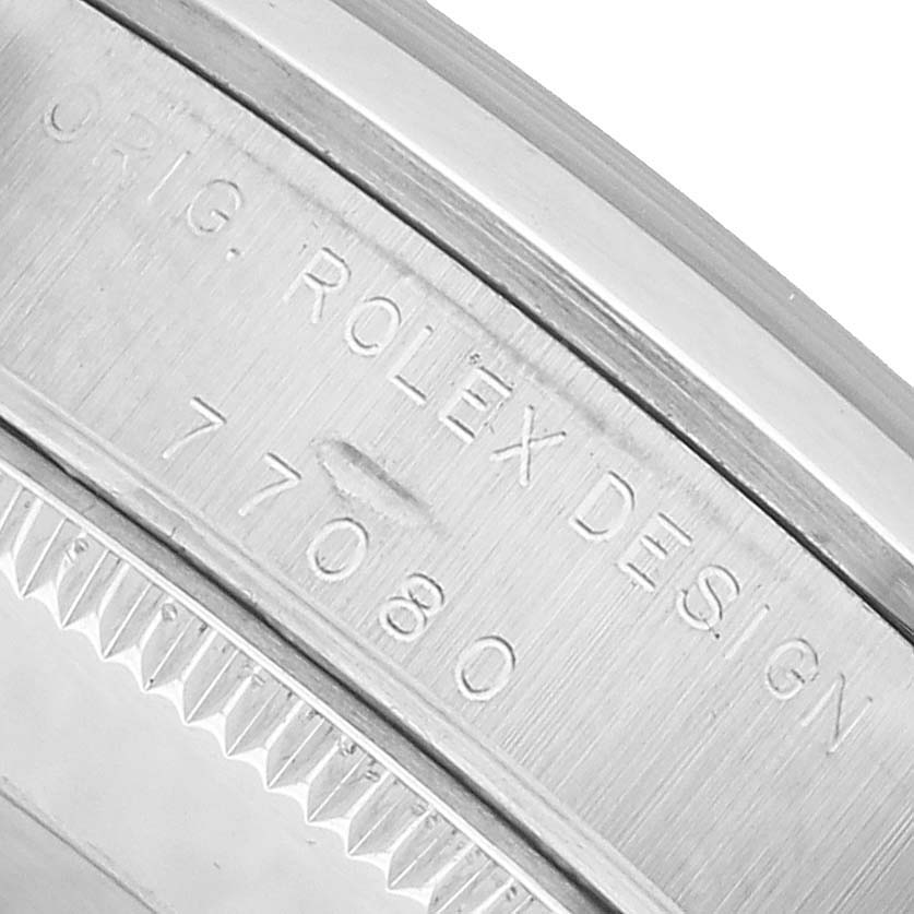 The angle shows the inner bezel of the mid-size Rolex watch engraved with "ORIG. ROLEX DESIGN 77080."