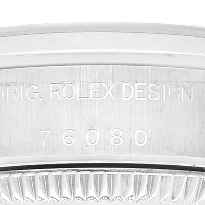 The image shows a close-up of the case and bezel of a Rolex Oyster Perpetual 76080 Women
s Stainless Steel Pink Dial 76080 Women
s Stainless Steel Pink Dial watch, featuring engraved text with the model number 76080.