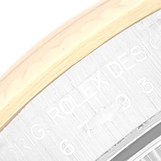 The image shows a close-up of the side engraving on a Rolex Oyster Perpetual 67193 Women's Steel and Gold (two tone) Blue Dial 67193 Women's Steel and Gold (two tone) Blue Dial watch, focusing on part of the bezel and the case.