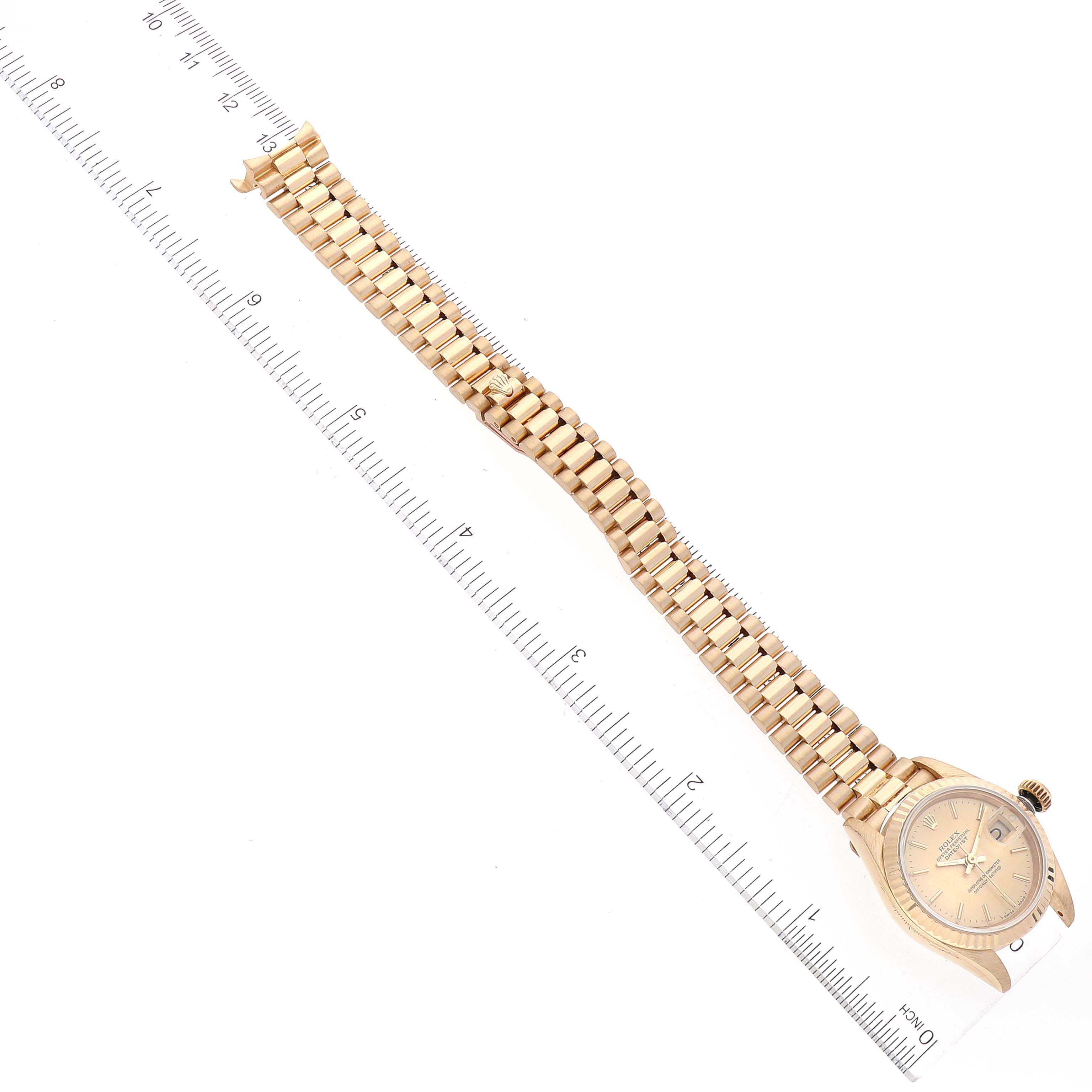 The image shows the Rolex President 69178 Women
s Yellow Gold Champagne Dial 69178 Women
s Yellow Gold Champagne Dial model watch laid flat with its bracelet and face visible, alongside a ruler for scale.