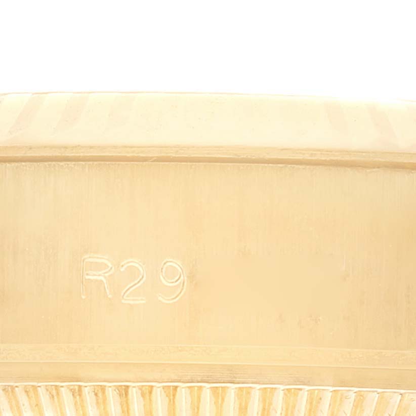 This image shows a close-up of the side and part of the bezel of a Rolex President 69178 Women
s Yellow Gold Champagne Dial 69178 Women
s Yellow Gold Champagne Dial model watch with the marking "R29."