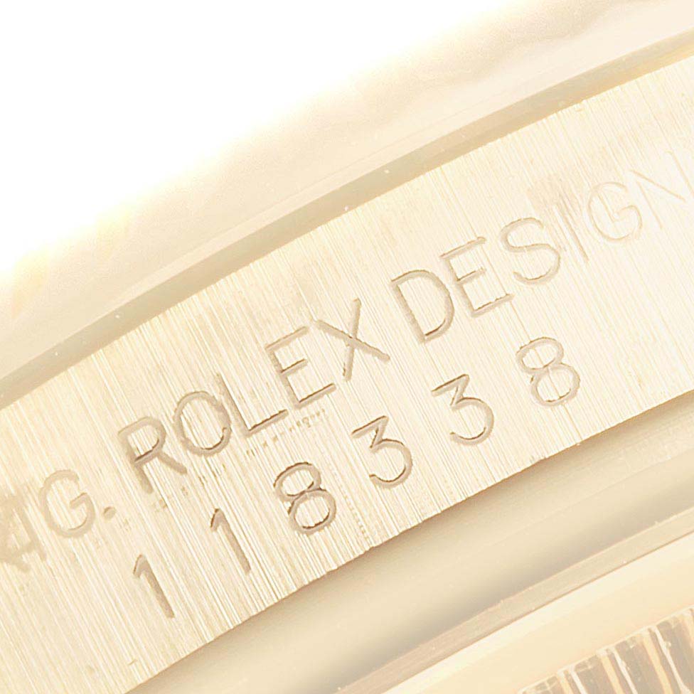 This image shows a close-up of the engraved serial number and "Rolex Design" text on the case edge of a Rolex President 118338 Men
s Yellow Gold Silver Dial 118338 Men
s Yellow Gold Silver Dial model watch.
