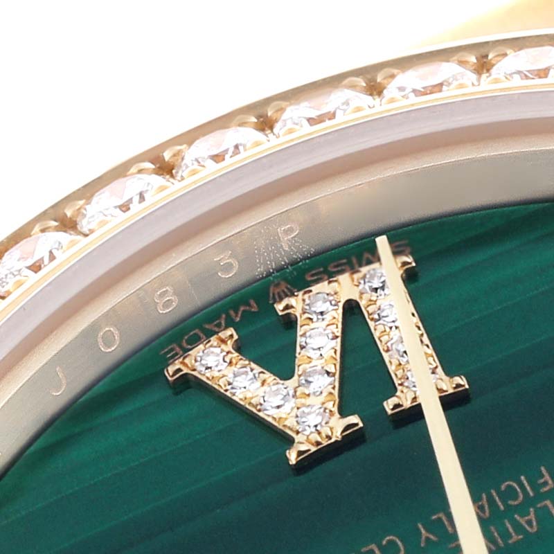 The image shows a close-up of the Rolex President 278288RBR Women
s Yellow Gold Green Dial 278288RBR Women
s Yellow Gold Green Dial model
s diamond-set bezel and roman numeral VI on the watch face.