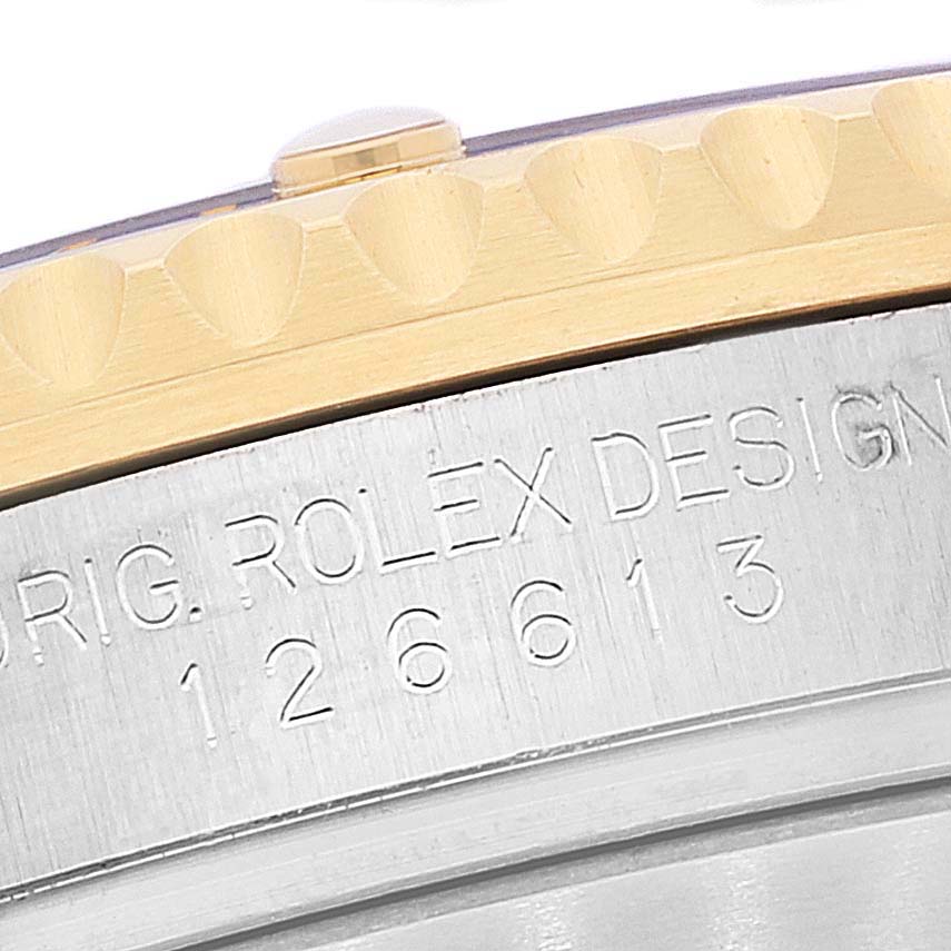 The image shows a close-up of the bezel and part of the case of a Rolex Submariner 126613 Men's Steel and Gold (two tone) Blue Dial 126613 Men's Steel and Gold (two tone) Blue Dial watch, featuring engraved text and a model number.