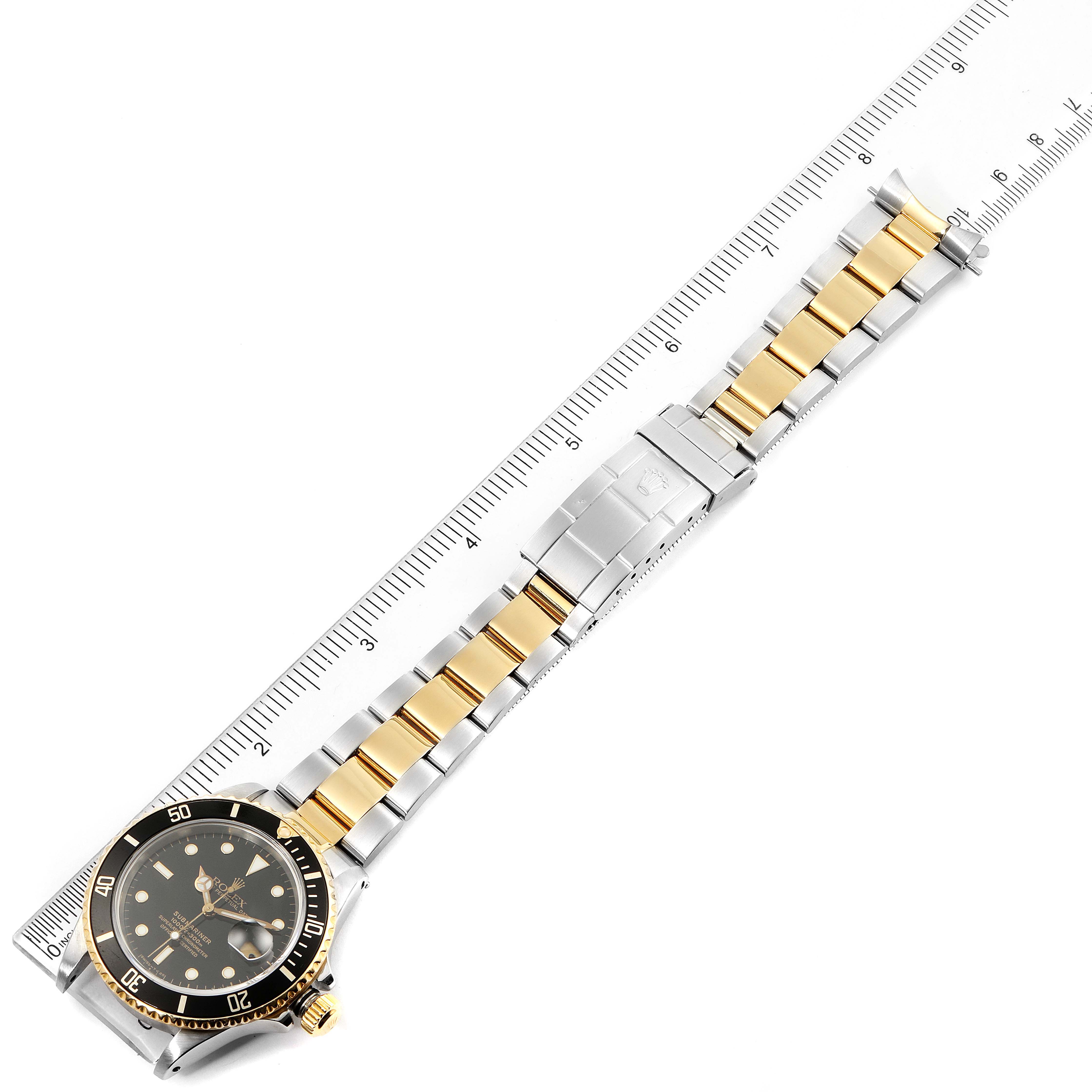 The image shows a Rolex Submariner 16803 Men's Steel and Gold (two tone) Black Dial 16803 Men's Steel and Gold (two tone) Black Dial watch, laid flat with its bracelet extended alongside a ruler for measurement.