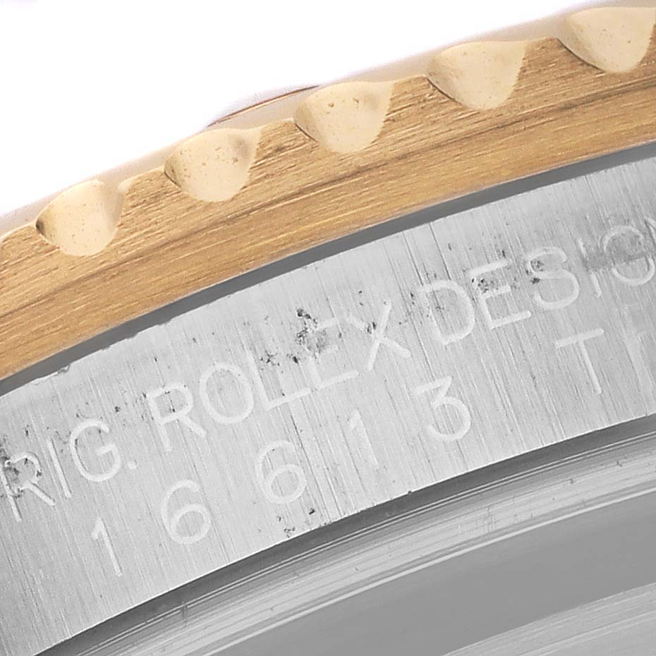 The image shows a close-up of the Rolex Submariner 16613 Men's Steel and Gold (two tone) Black Dial 16613 Men's Steel and Gold (two tone) Black Dial's bezel edge and side engraving.