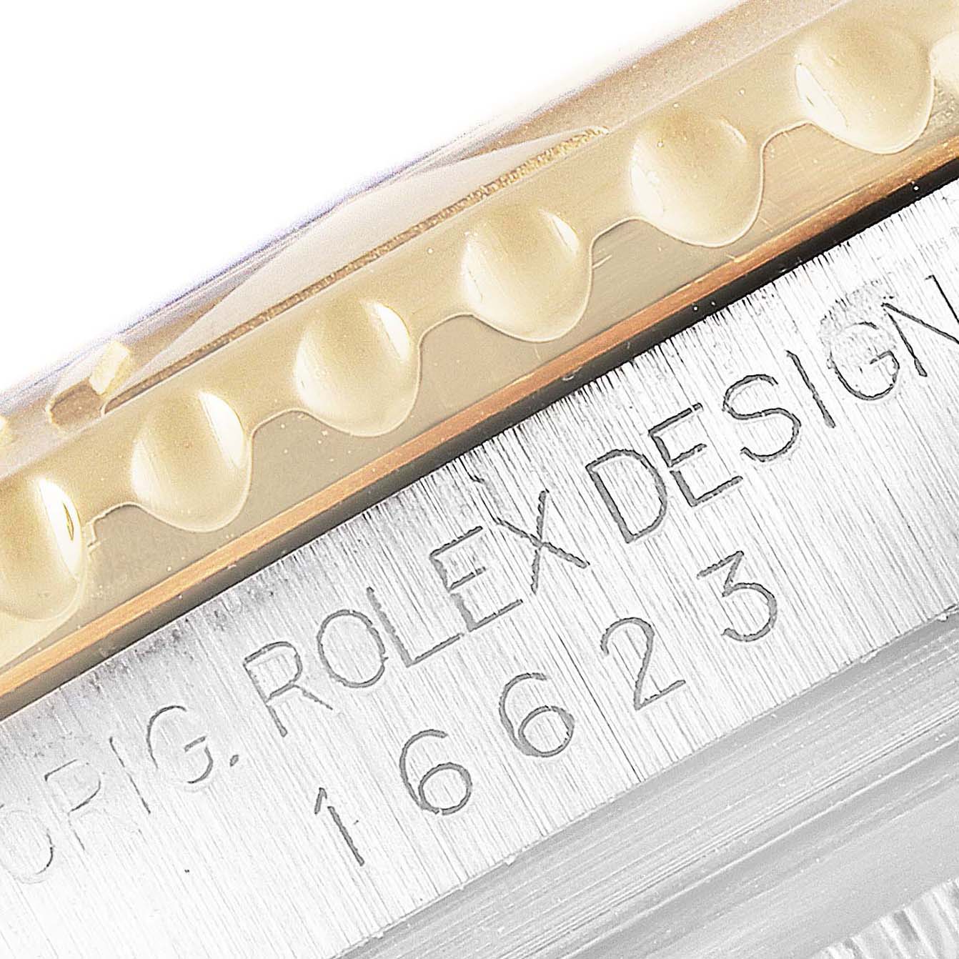 This close-up shows the side of the bezel and part of the case with engraved text on a Rolex Yacht-Master 16623 Men's Steel and Gold (two tone) Blue Dial 16623 Men's Steel and Gold (two tone) Blue Dial watch.