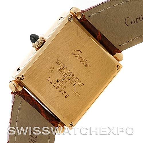 The image shows the back case and part of the strap of a Cartier Tank Obus Yellow Gold Silver Dial Yellow Gold Silver Dial watch, focusing on the inscriptions and details.