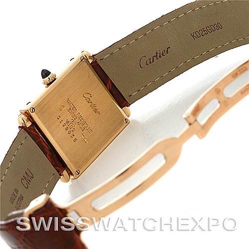 This image shows the back and strap of a Cartier Tank Obus Yellow Gold Silver Dial Yellow Gold Silver Dial watch, highlighting the watch's engravings and leather strap.