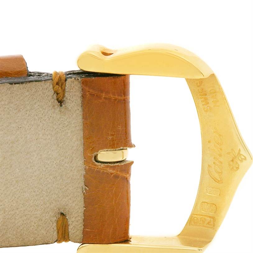 This image shows a close-up of the leather strap and gold buckle of the Tank Obus model by Cartier.